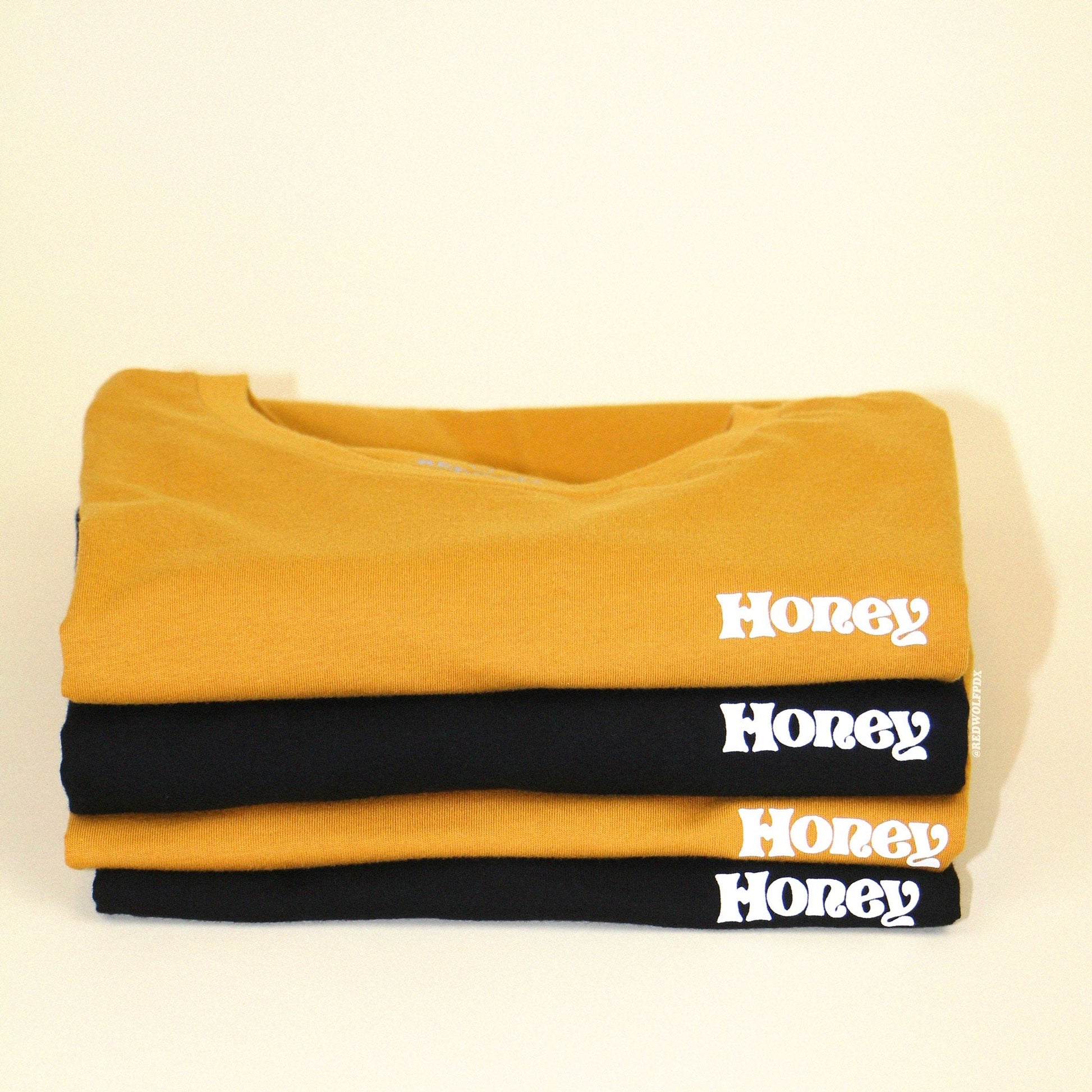 stack of folded tees with text 'Honey' on a white backdrop
