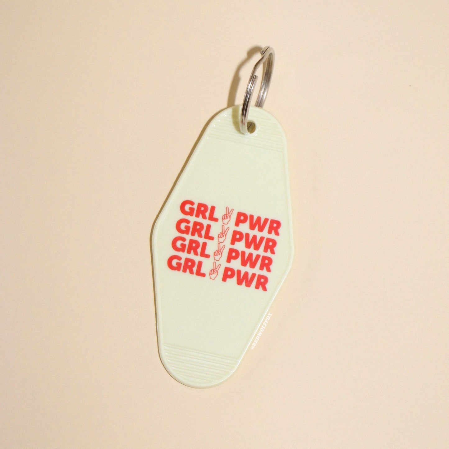 A vintage white keychain with the text 'GRL PWR' in red.