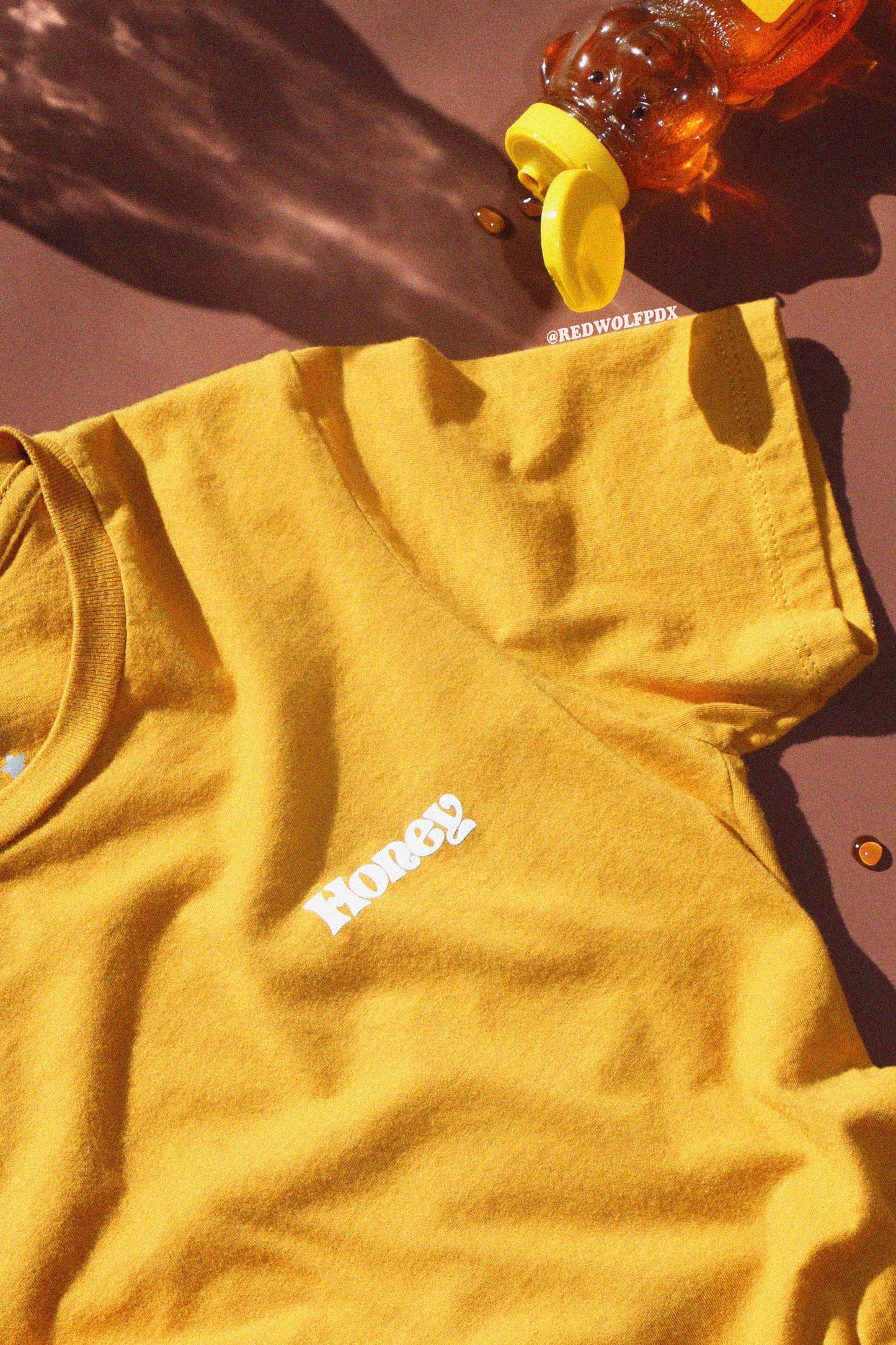 Yellow t-shirt with text 'Honey' in 70's vintage inspired font on a brown background