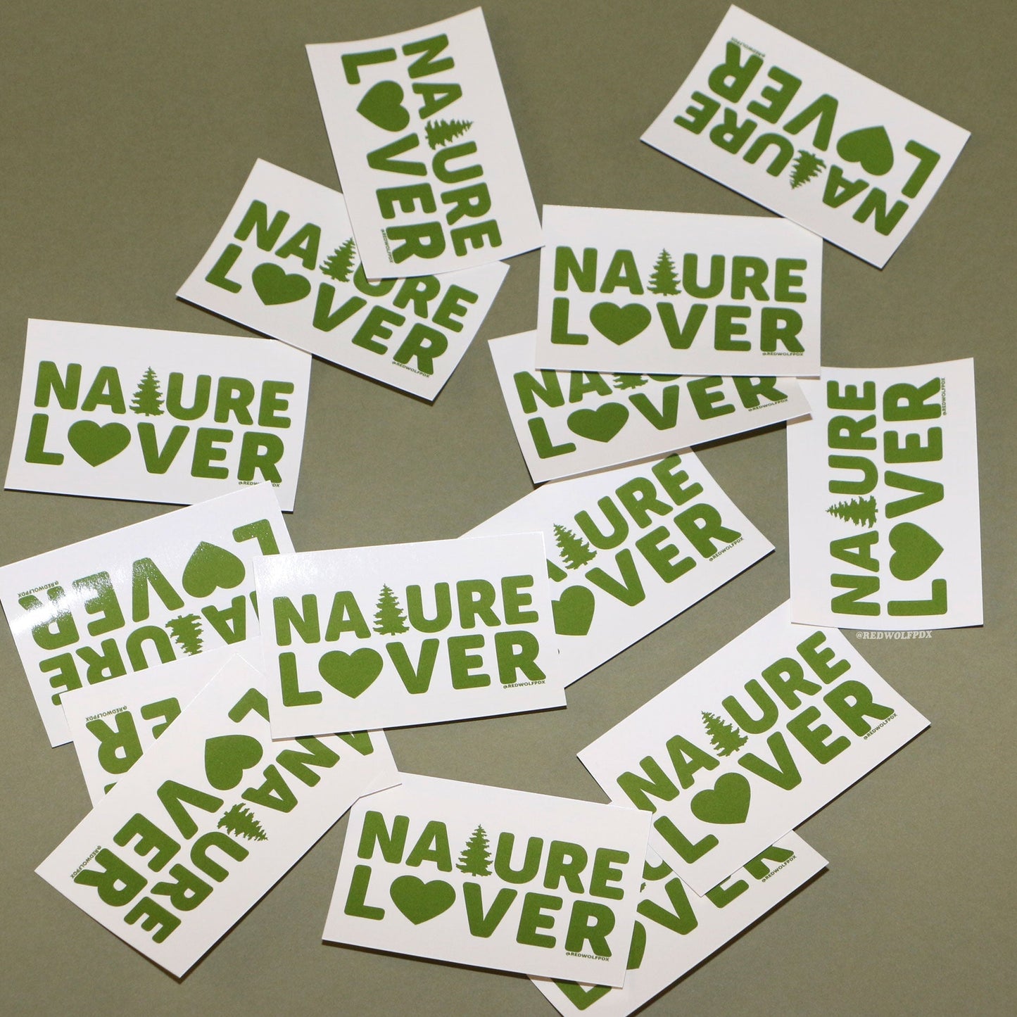 Rectangle beige stickers with text 'NATURE LOVER' in green ink scattered on a green backdrop