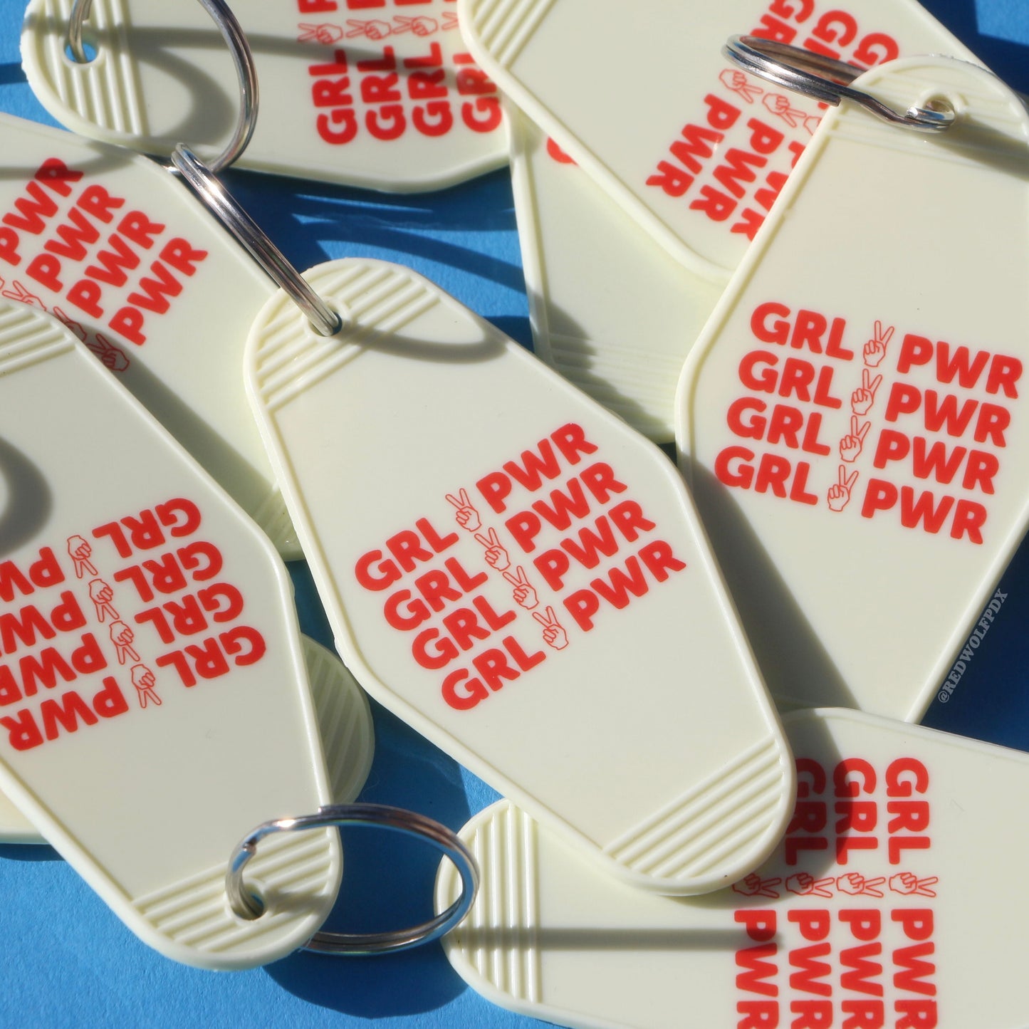 A pile of vintage white keychains with the text 'GRL PWR' in red on a retro blue background