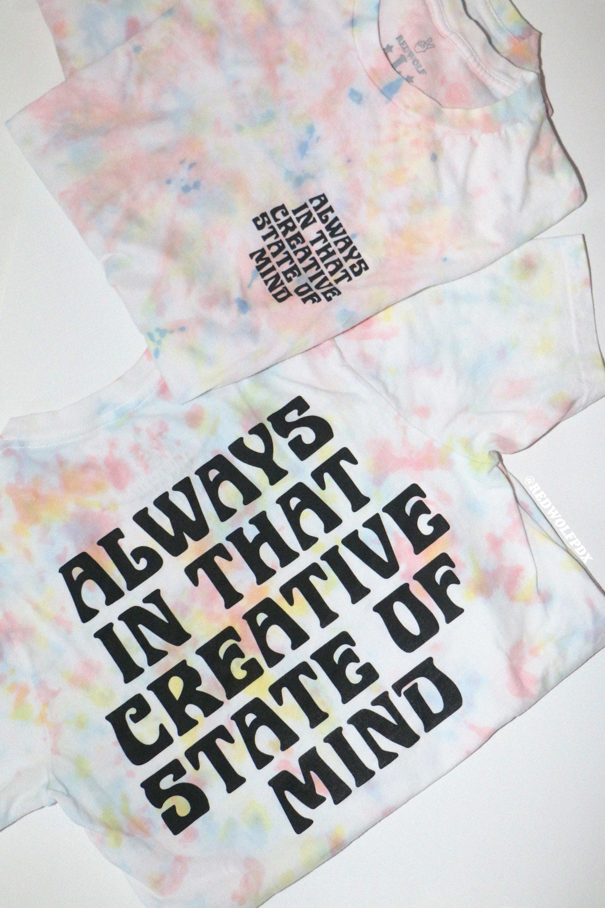 tie dye tees with text 'ALWAYS IN THAT CREATIVE STATE OF MIND' screen printed on front and back of tees on a white background.