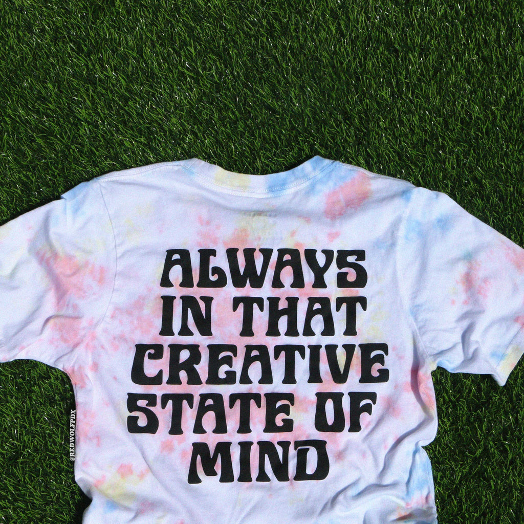 Tie-dye t-shirt with 'Always in that creative state of mind' text on grass
