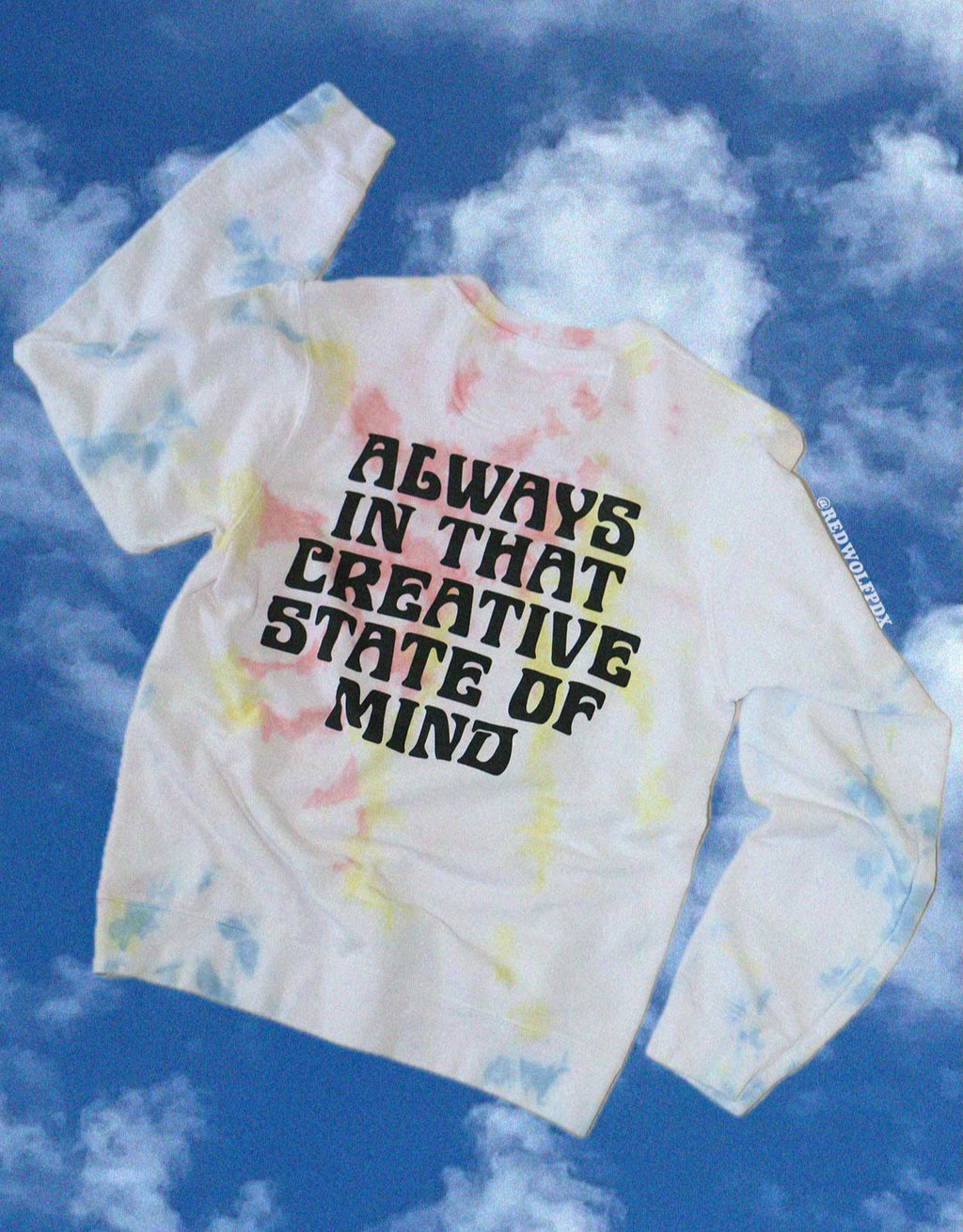 Tie-dye shirt with text 'Always in that creative state of mind' against a blue sky background