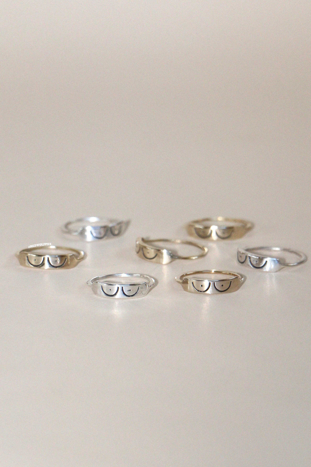 A collection of rings with a boob illustration etched into them, displayed on a light background.