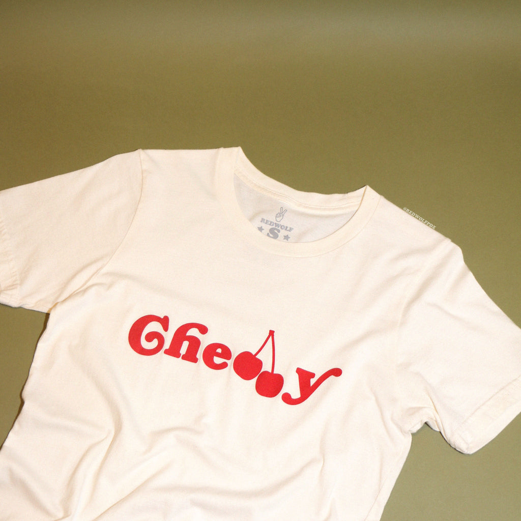 beige white graphic tee with text 'Cherry' screen printed across in red ink on a vintage green background