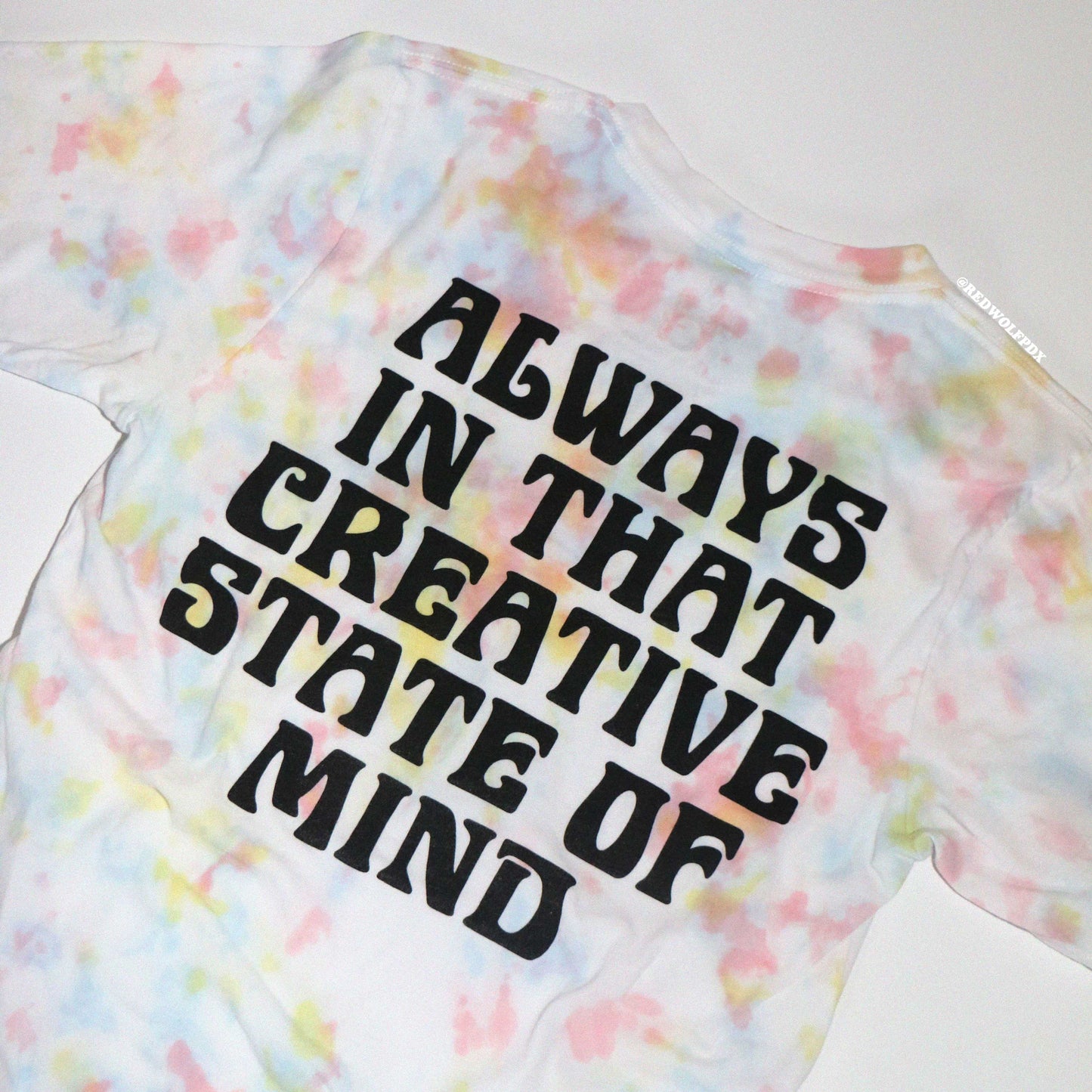 Tie-dye t-shirt with text 'ALWAYS IN THAT CREATIVE STATE OF MIND' screen printed on a plain background