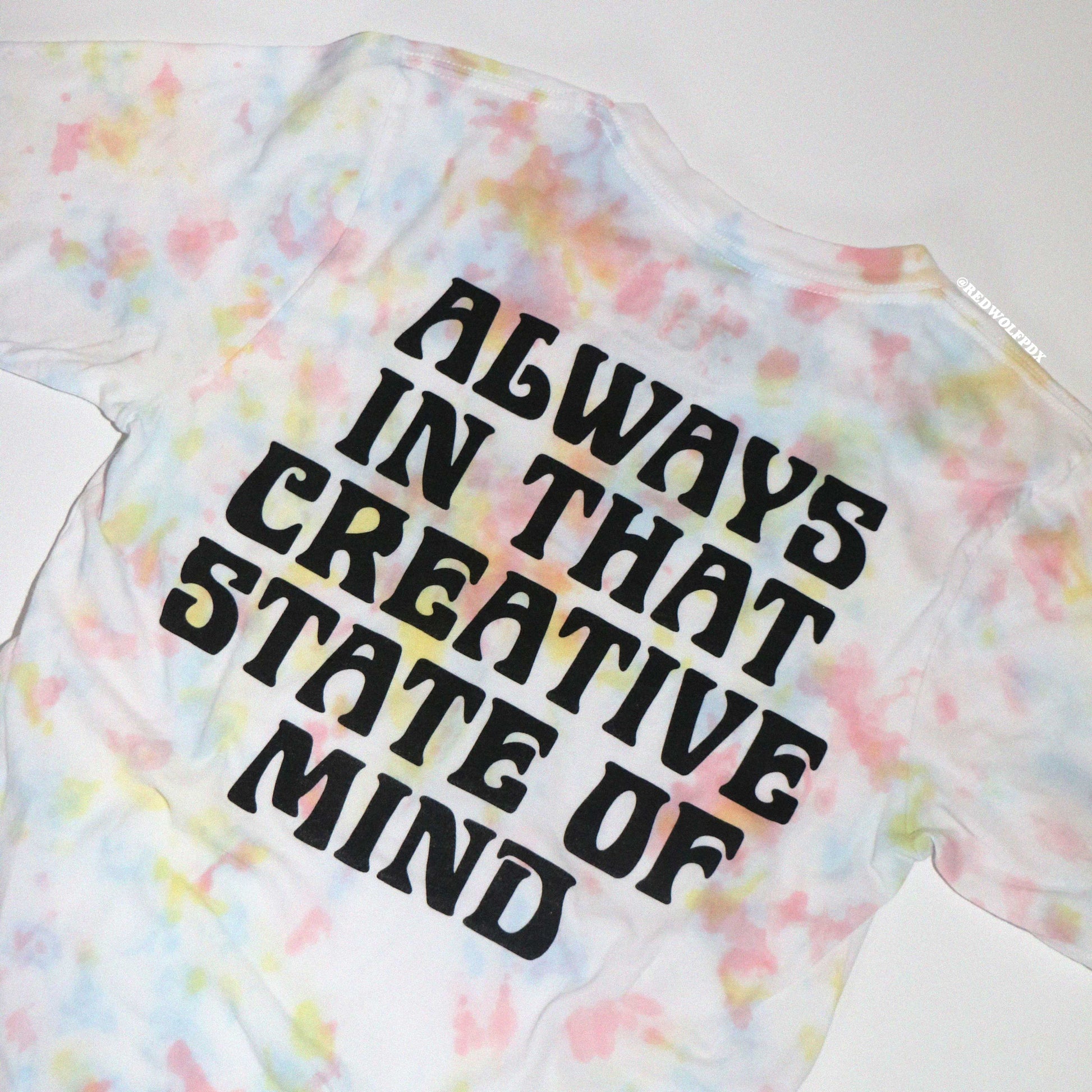 Tie-dye t-shirt with text 'ALWAYS IN THAT CREATIVE STATE OF MIND' screen printed on a plain background