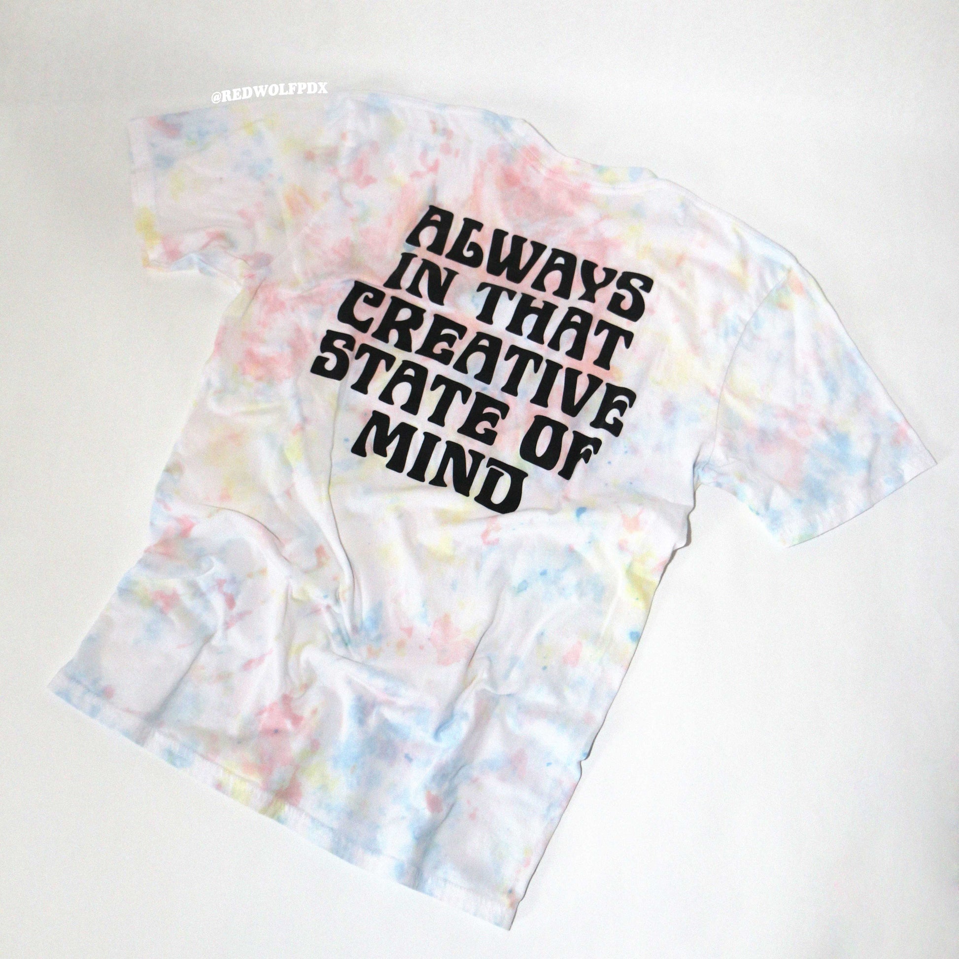 Tie-dye t-shirt with text 'Always in that creative state of mind' on a white background