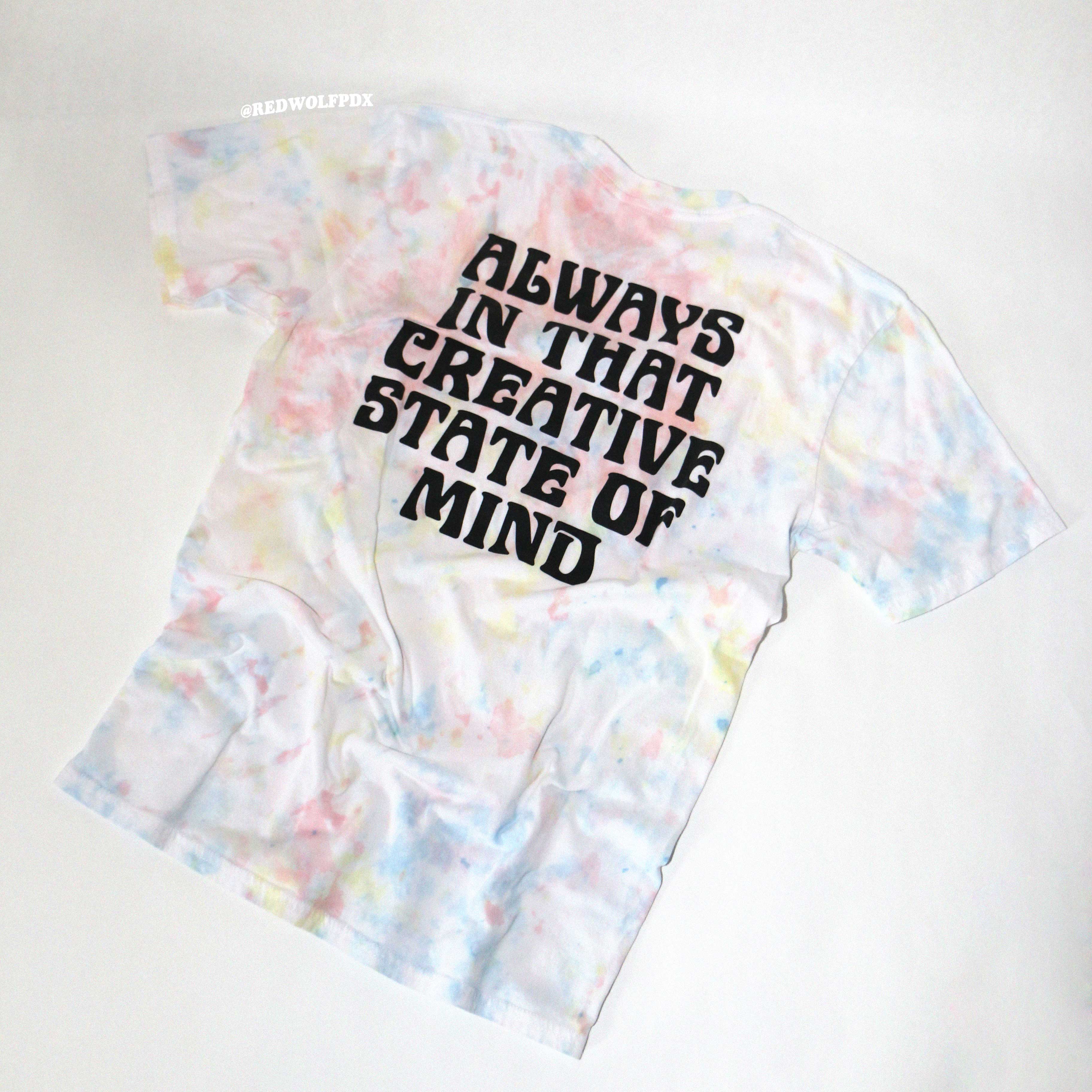 Tie-dye t-shirt with text 'Always in that creative state of mind' on a white background