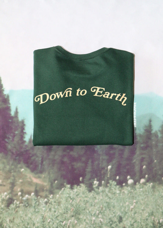 Green sweatshirt with 'Down to Earth' text on a blurred nature background