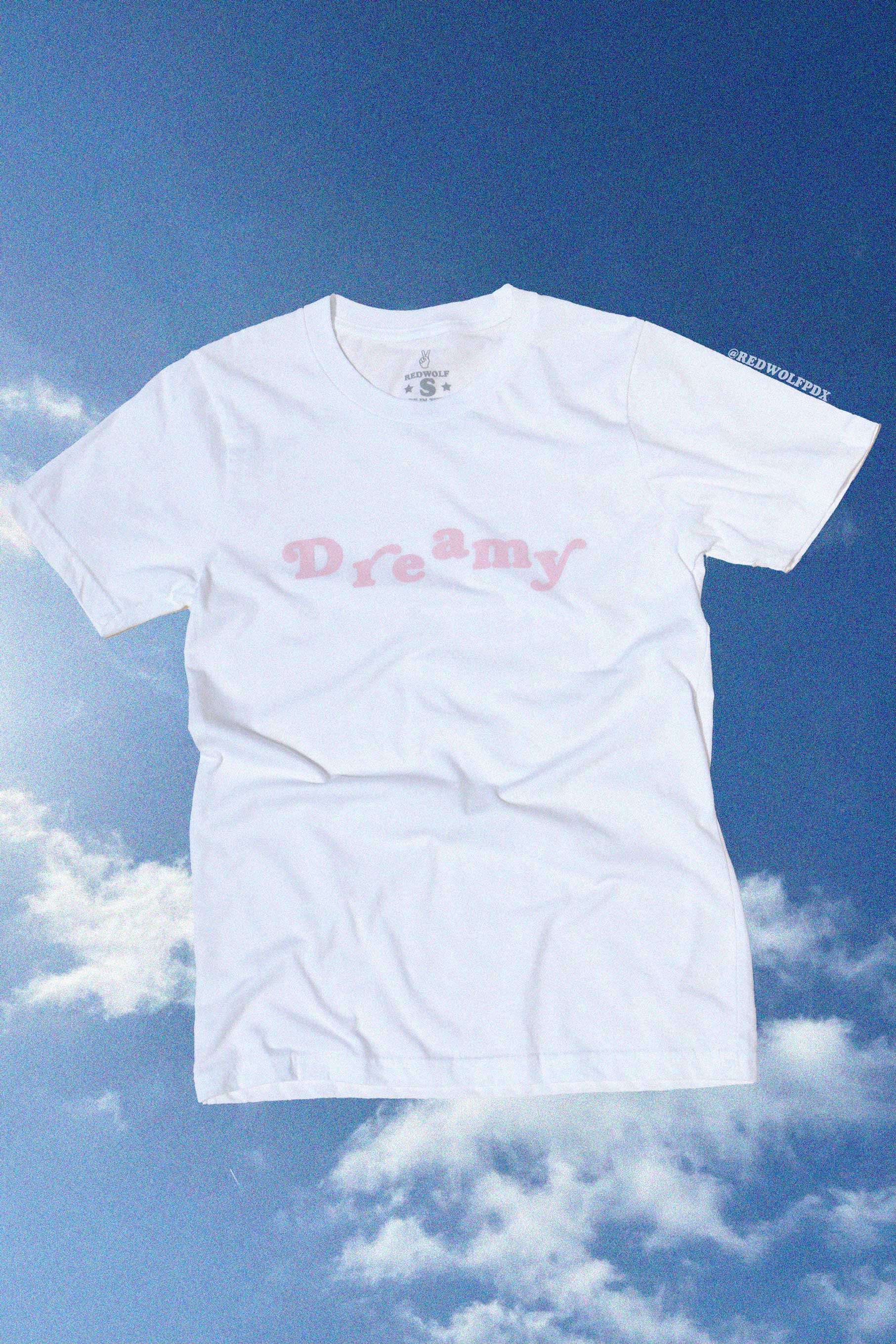 White t-shirt with 'Dreamy' text against a blue sky background