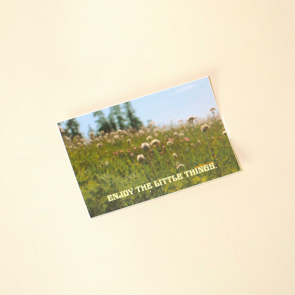 rectangle sticker of a photograph of  field of wildflowers and 'Enjoy the little things' text on a beige background