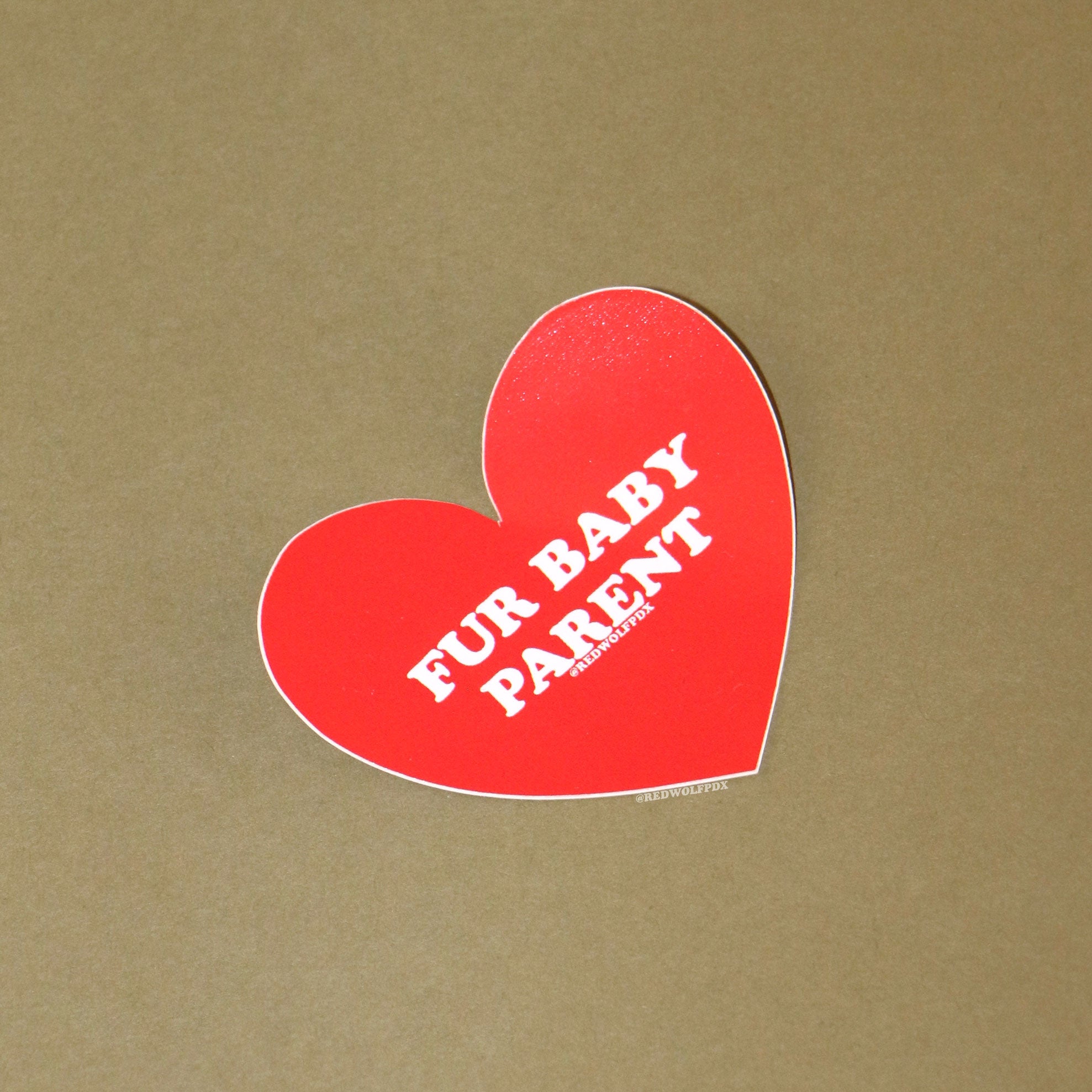 heart shaped red sticker with text 'FUR BABY PARENT' across it on a vintage green background