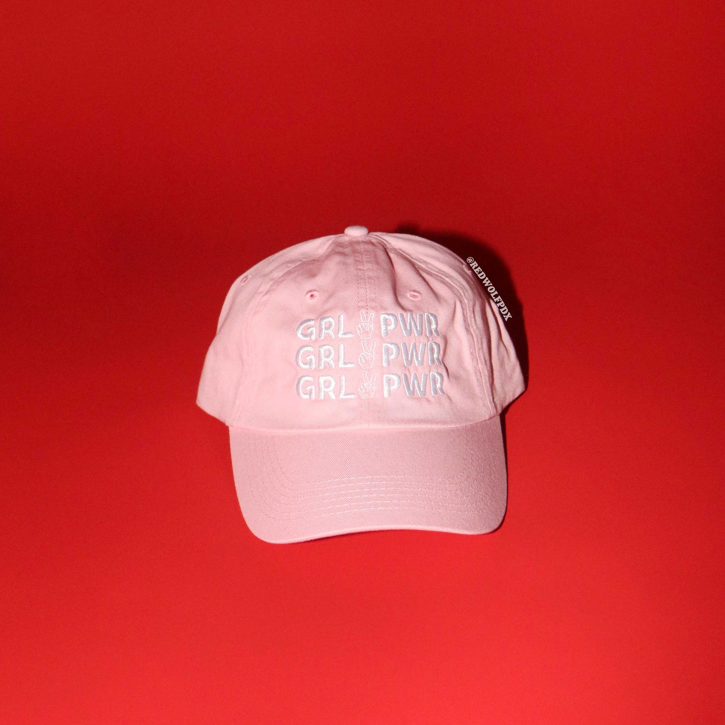 Pink cap with 'GRL PWR' text on a red background
