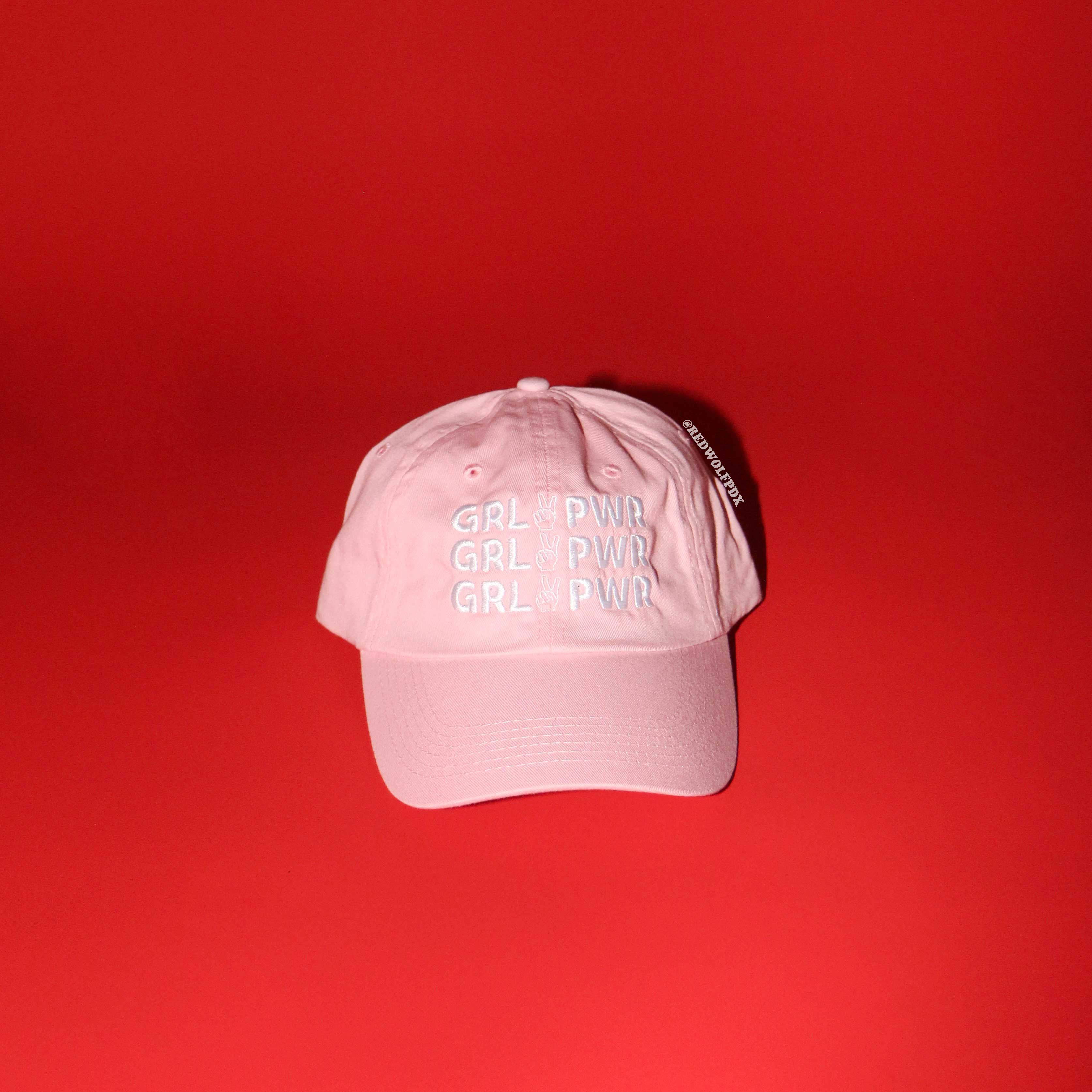 Pink cap with 'GRL PWR' text on a red background