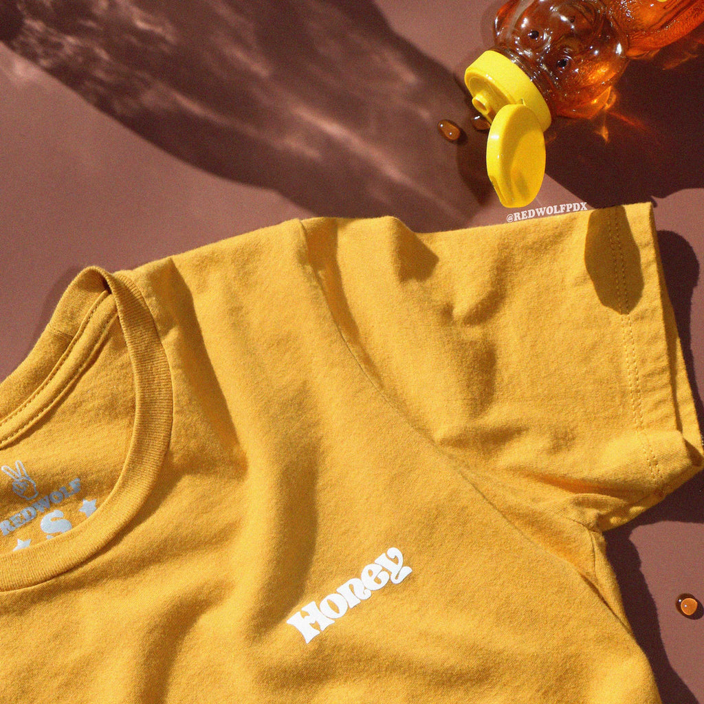 Yellow t-shirt with 'Honey' text on a brown background