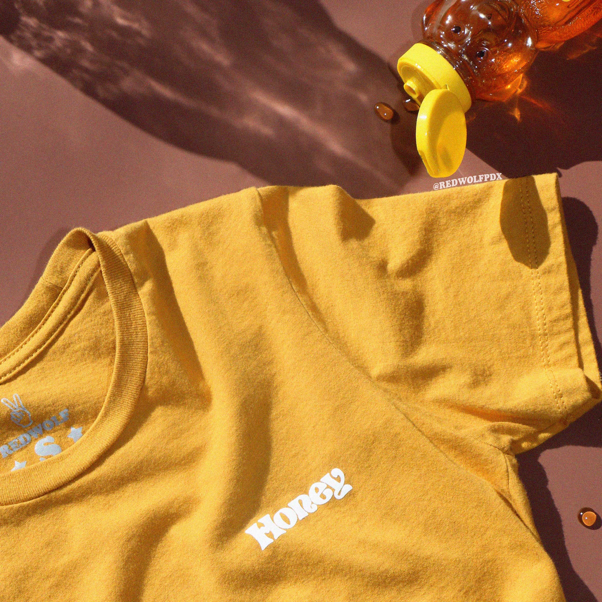 Yellow t-shirt with 'Honey' text on a brown background