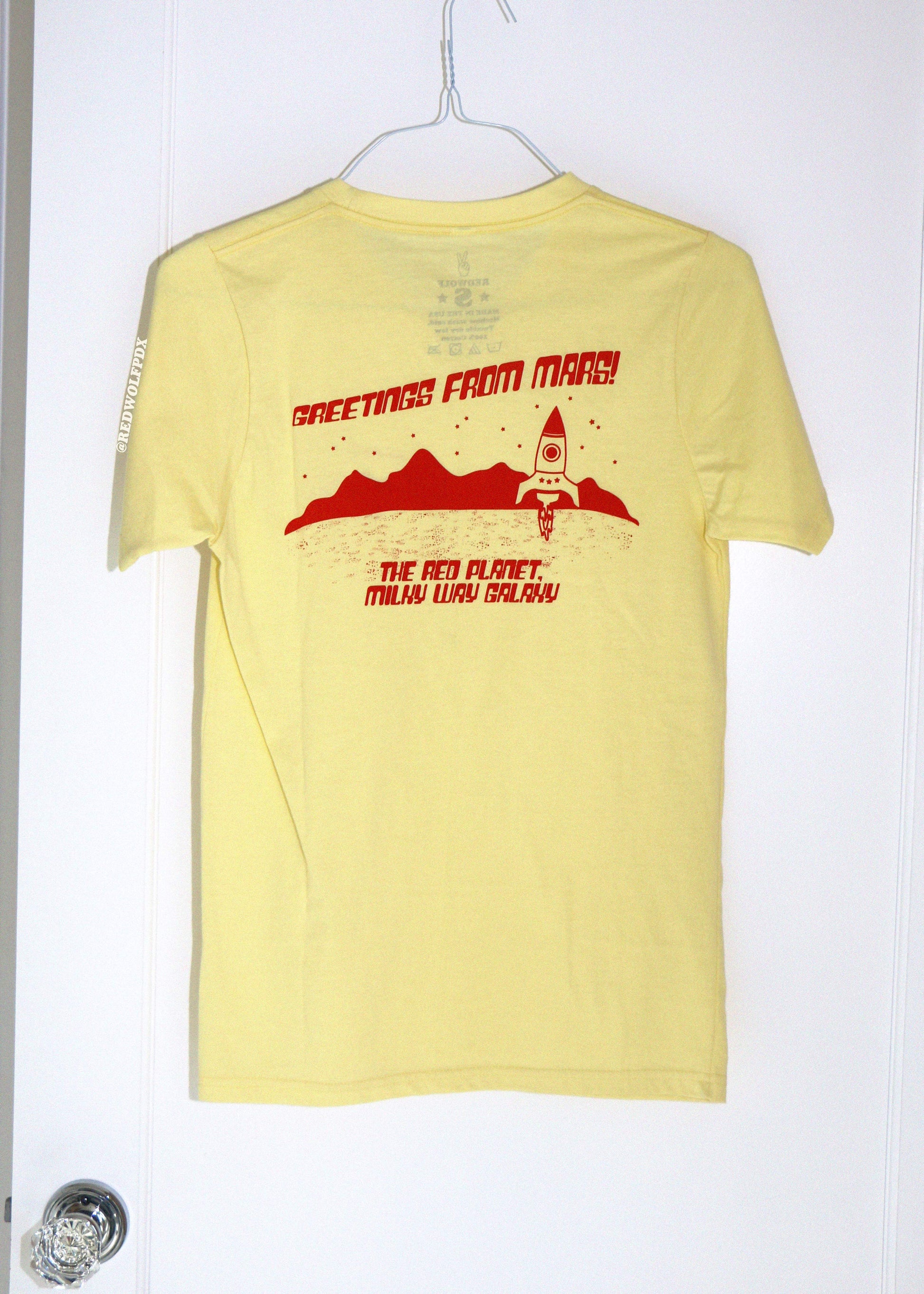 Yellow t-shirt with red graphic and text on a white background