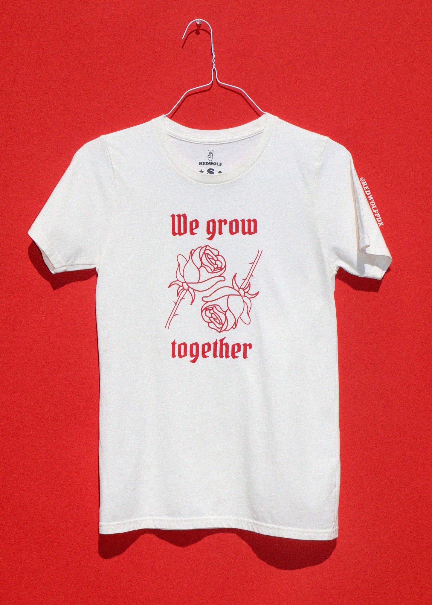 White t-shirt with red text and roses on a red background