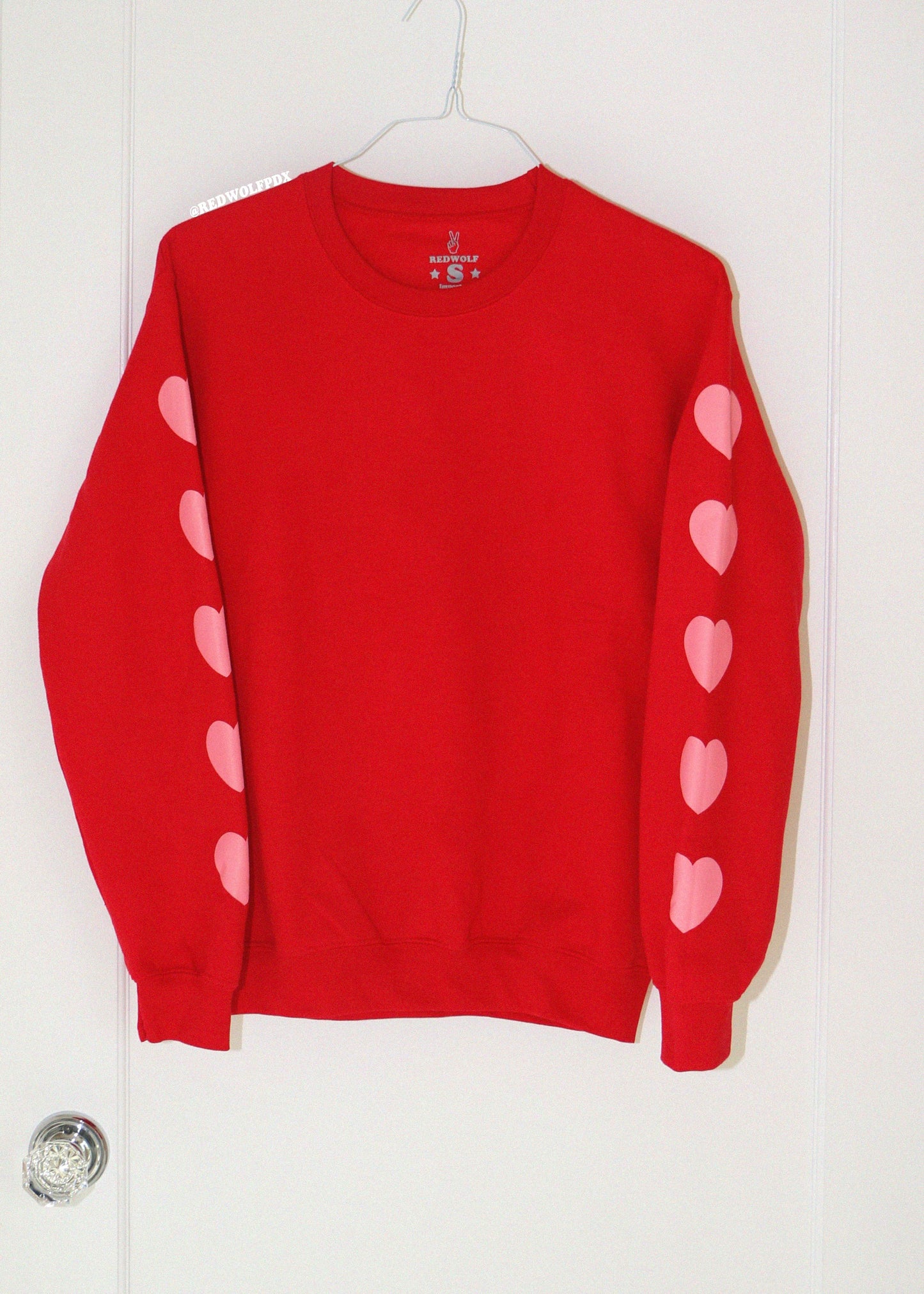 Red sweater with pink heart designs on a white background