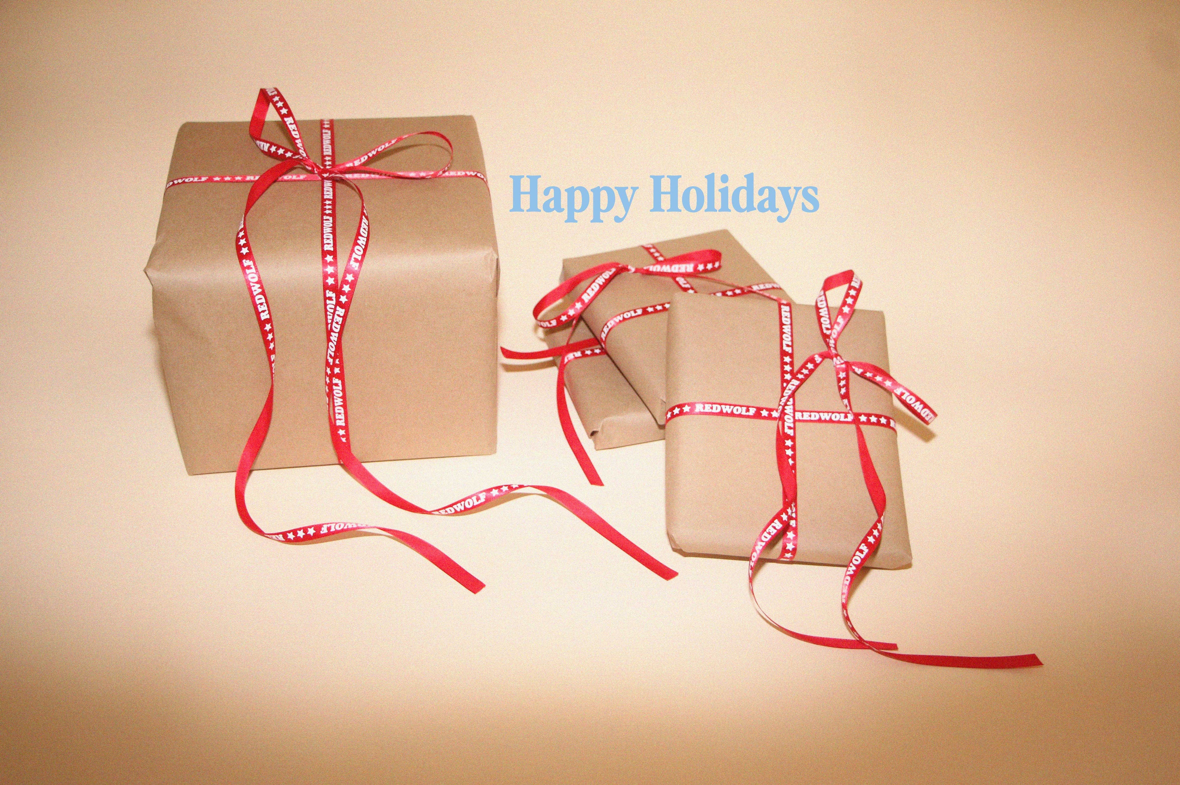 Two brown gift boxes with red ribbons on a beige background, featuring 'Happy Holidays' text.