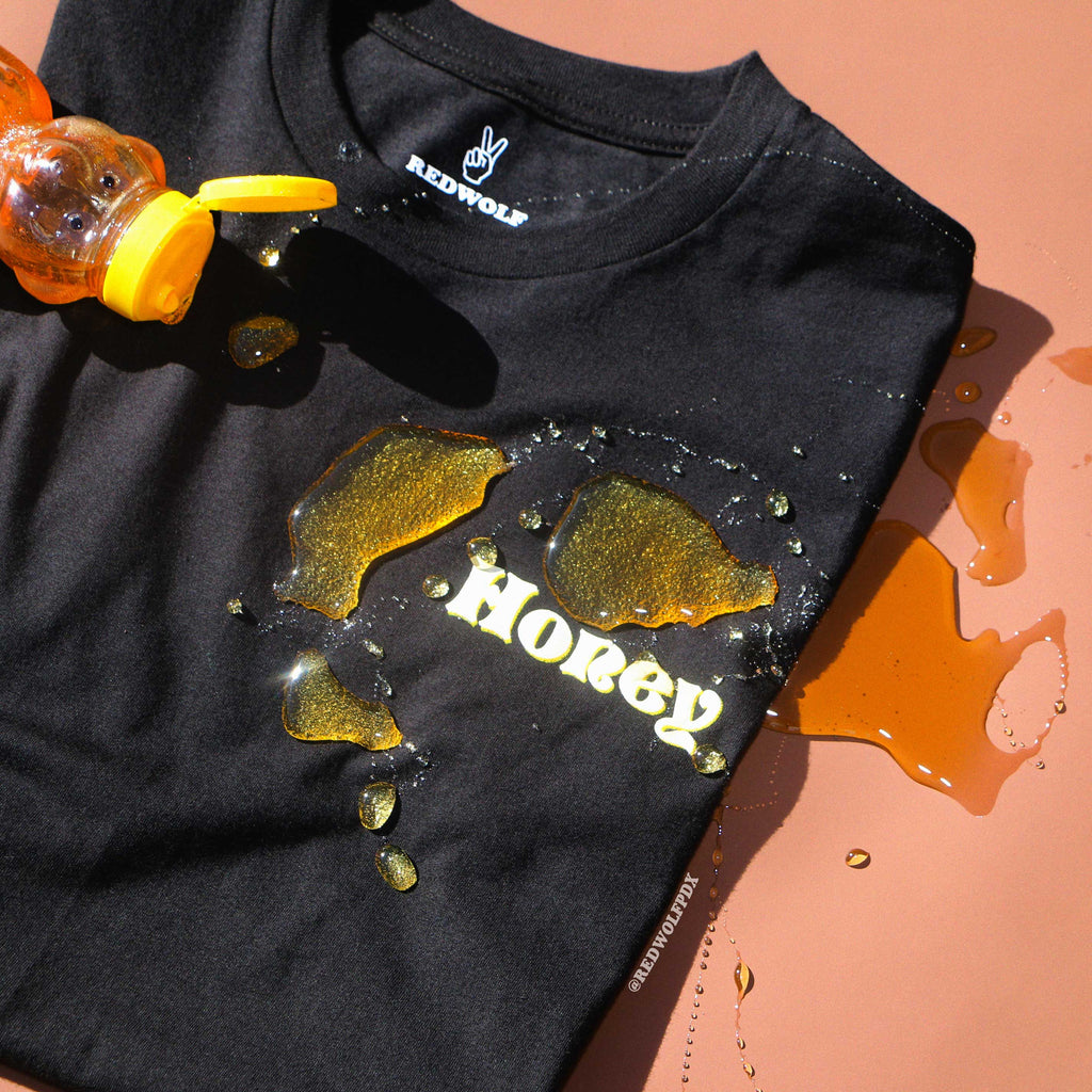 Black t-shirt with 'Honey' text and honey graphics on a peach background