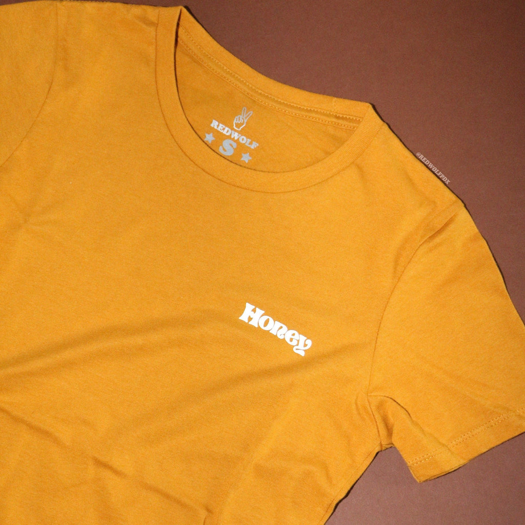 Vintage golden yellow graphic tee with text 'Honey' white ink screen printed on front corner chest on a brown background