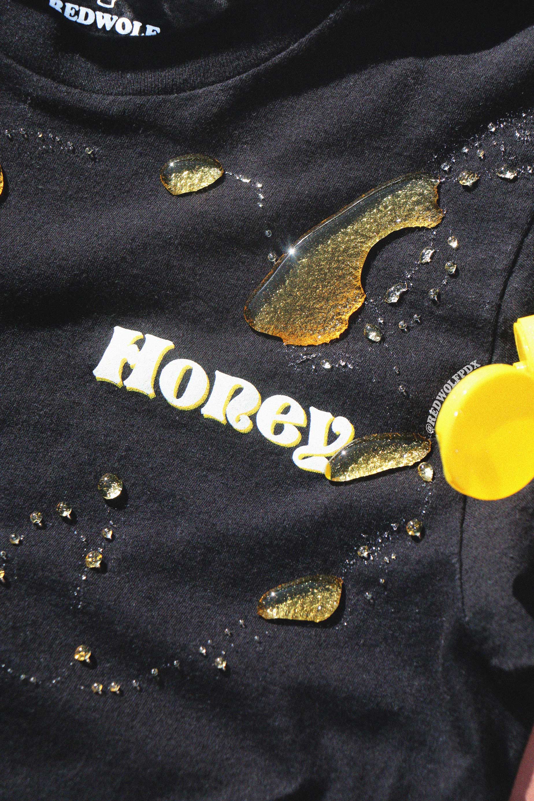 Black tee with 'Honey' text with honey spilled across tee