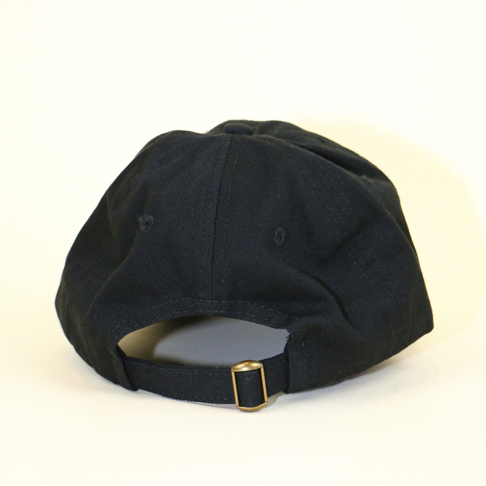 back of black baseball cap that is adjustable on beige backdrop