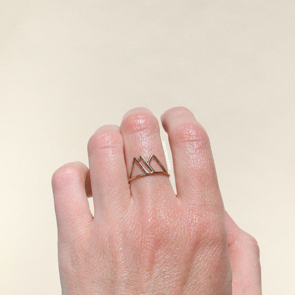 brass mountain outline ring being worn against a beige backdrop