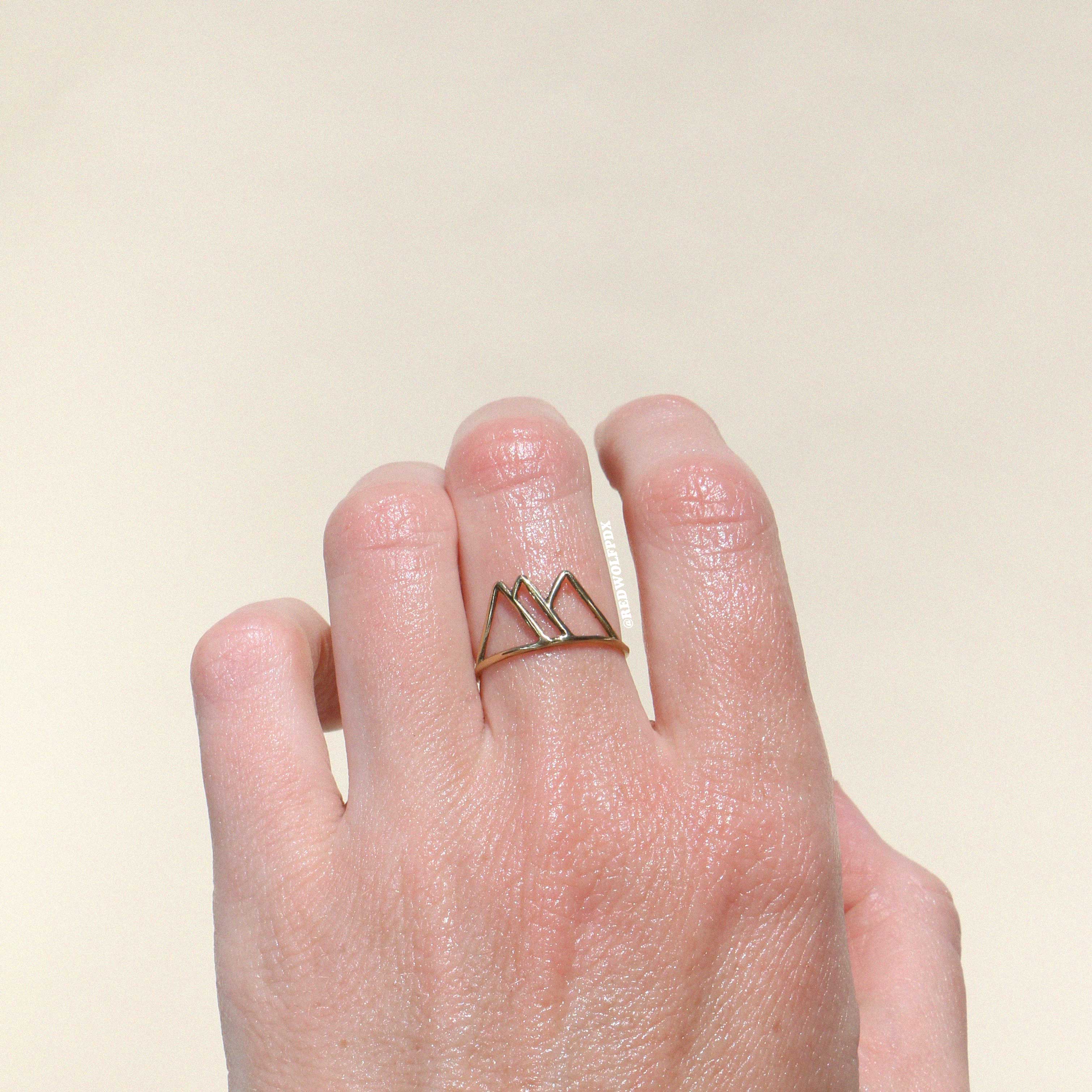 brass mountain outline ring being worn against a beige backdrop