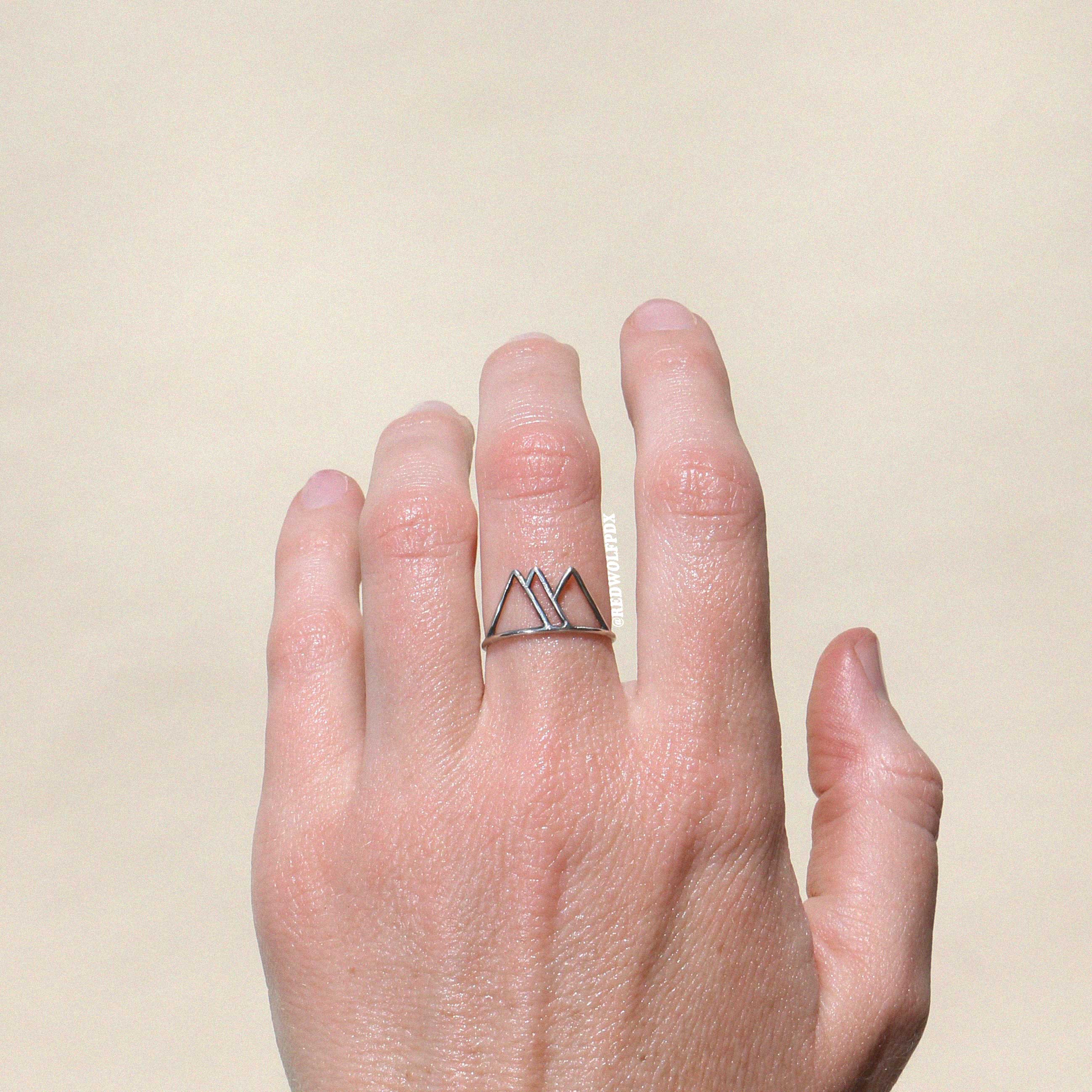 sterling silver mountain outline ring being worn against a beige backdrop