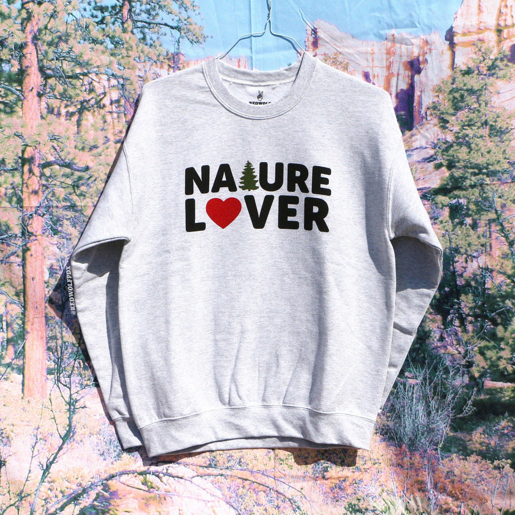 'NATURE LOVER' text graphic on gray crewneck sweatshirt on nature landscape backdrop