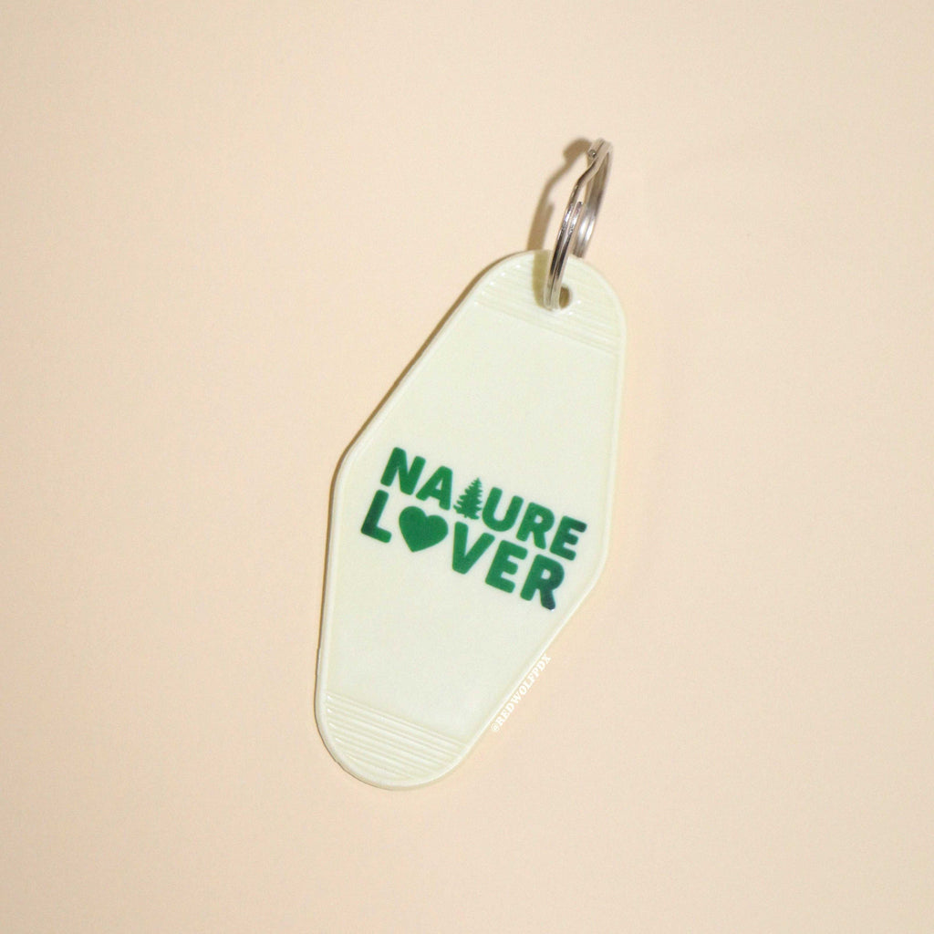 A vintage white keychain with the text 'NATURE LOVER' in dark green, shaped like a motel key.