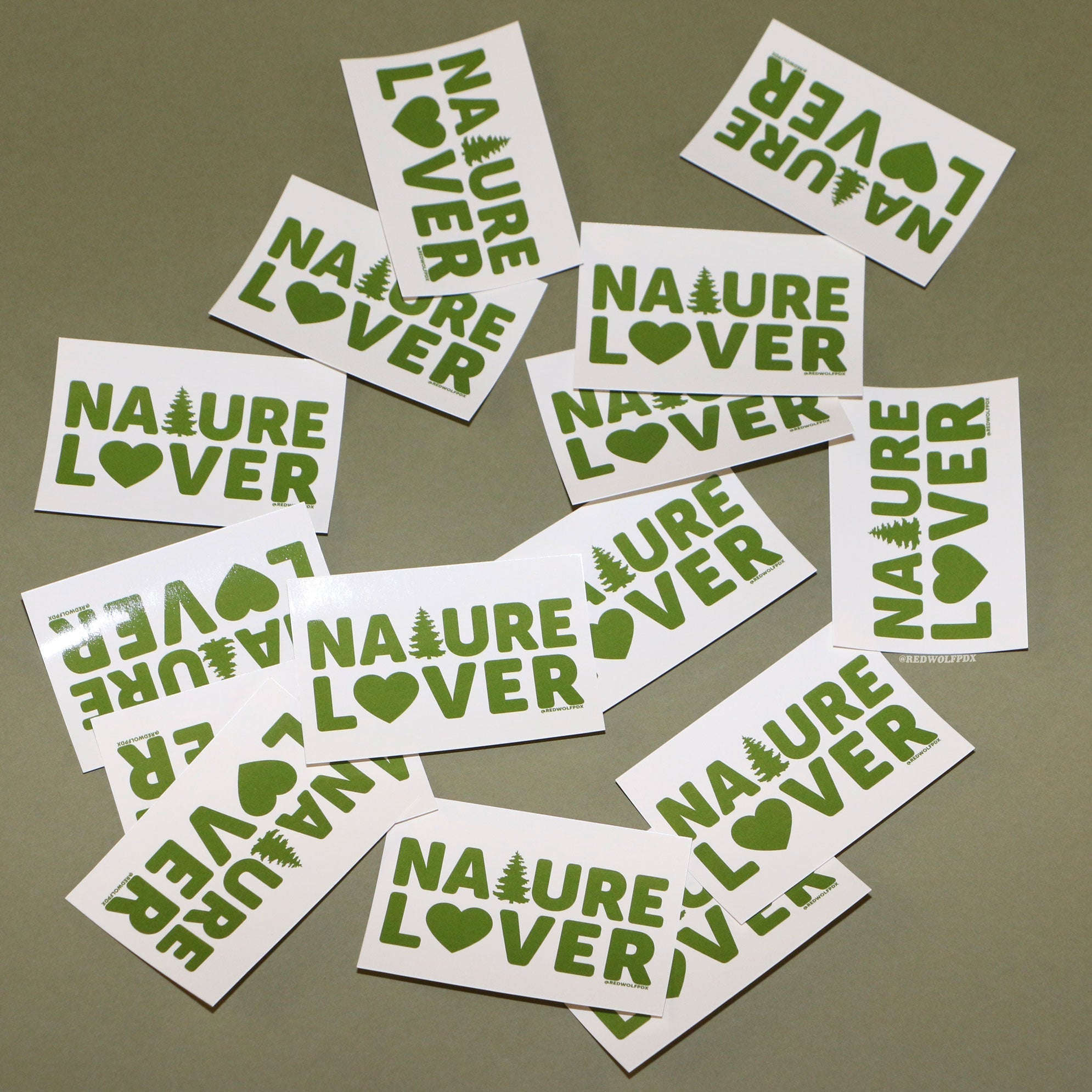 Rectangle beige stickers with text 'NATURE LOVER' in green ink scattered on a green backdrop