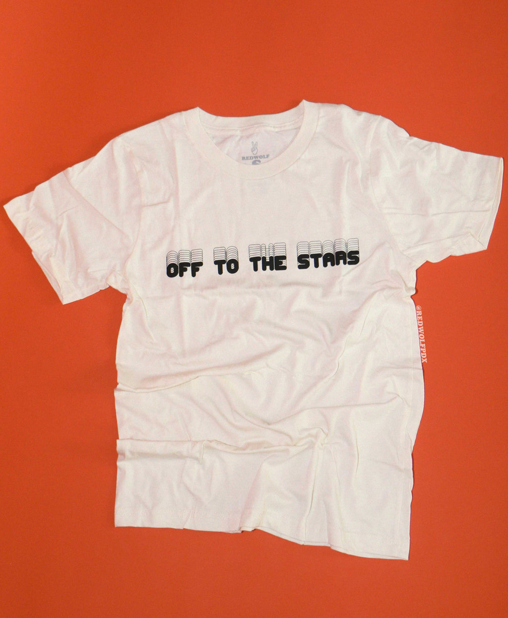 White t-shirt with text 'OFF TO THE STARS' on a red background