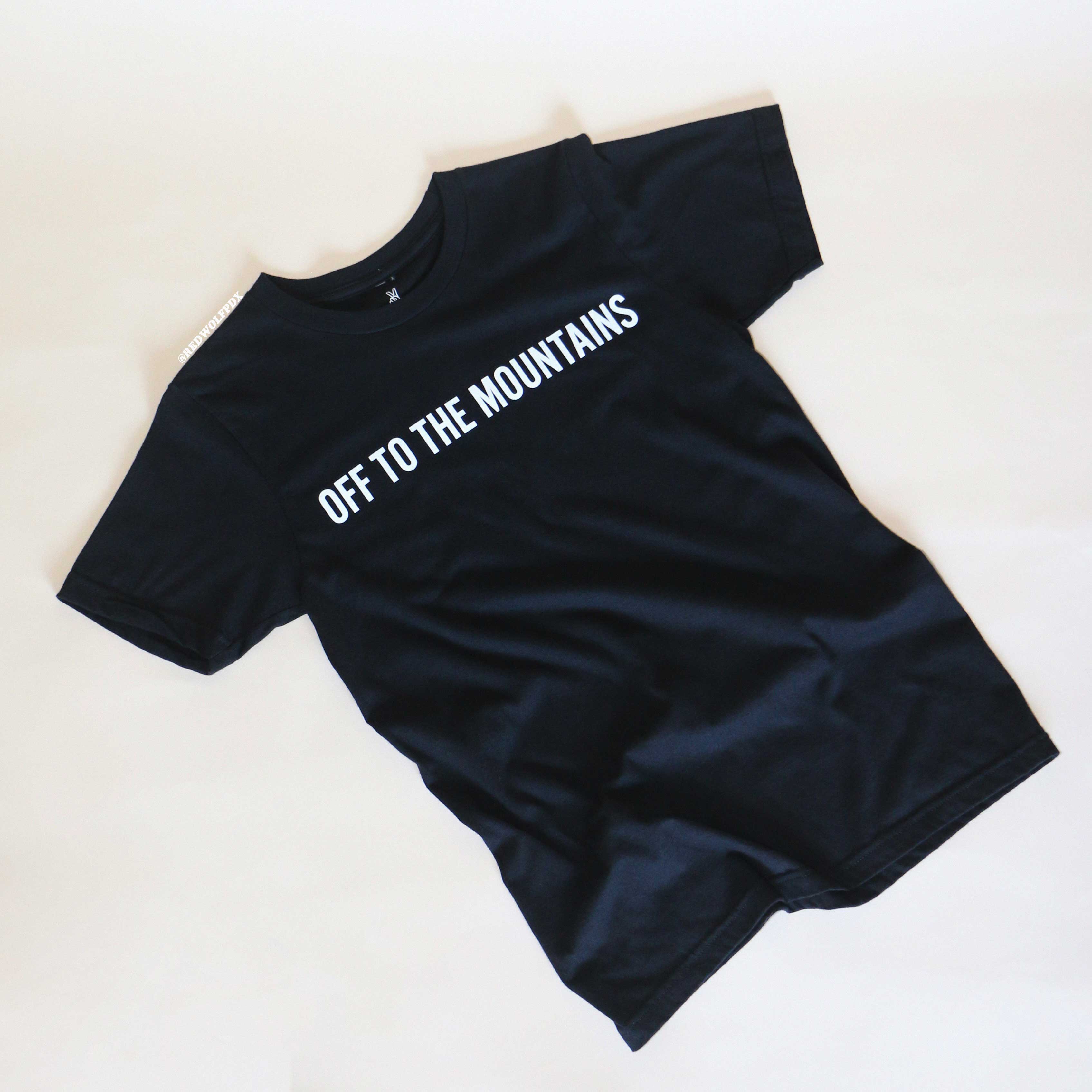 Black t-shirt with 'OFF TO THE MOUNTAINS' text on a white background