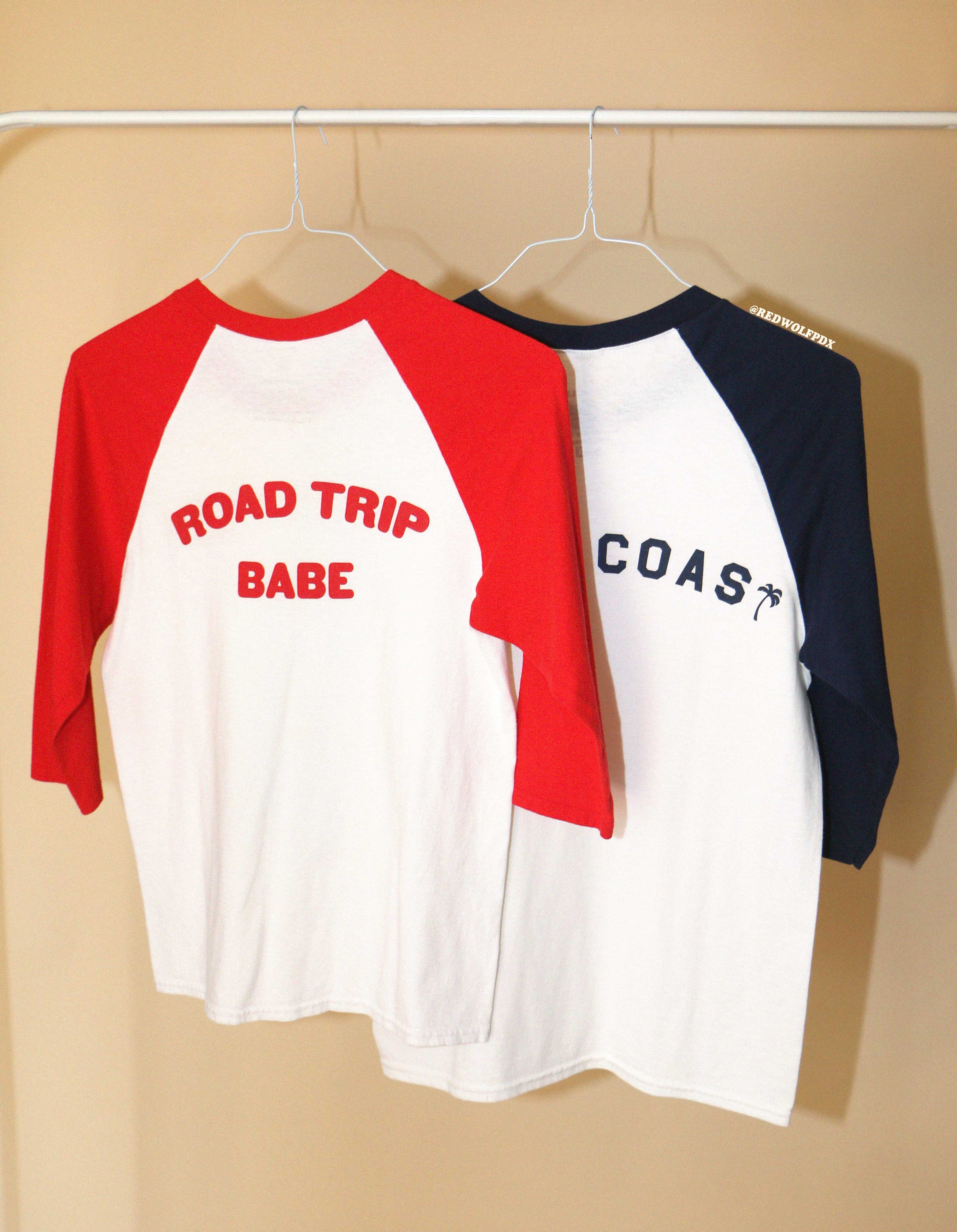 Two baseball shirts hanging on a rack with 'ROAD TRIP BABE' and 'WEST COAST' text.
