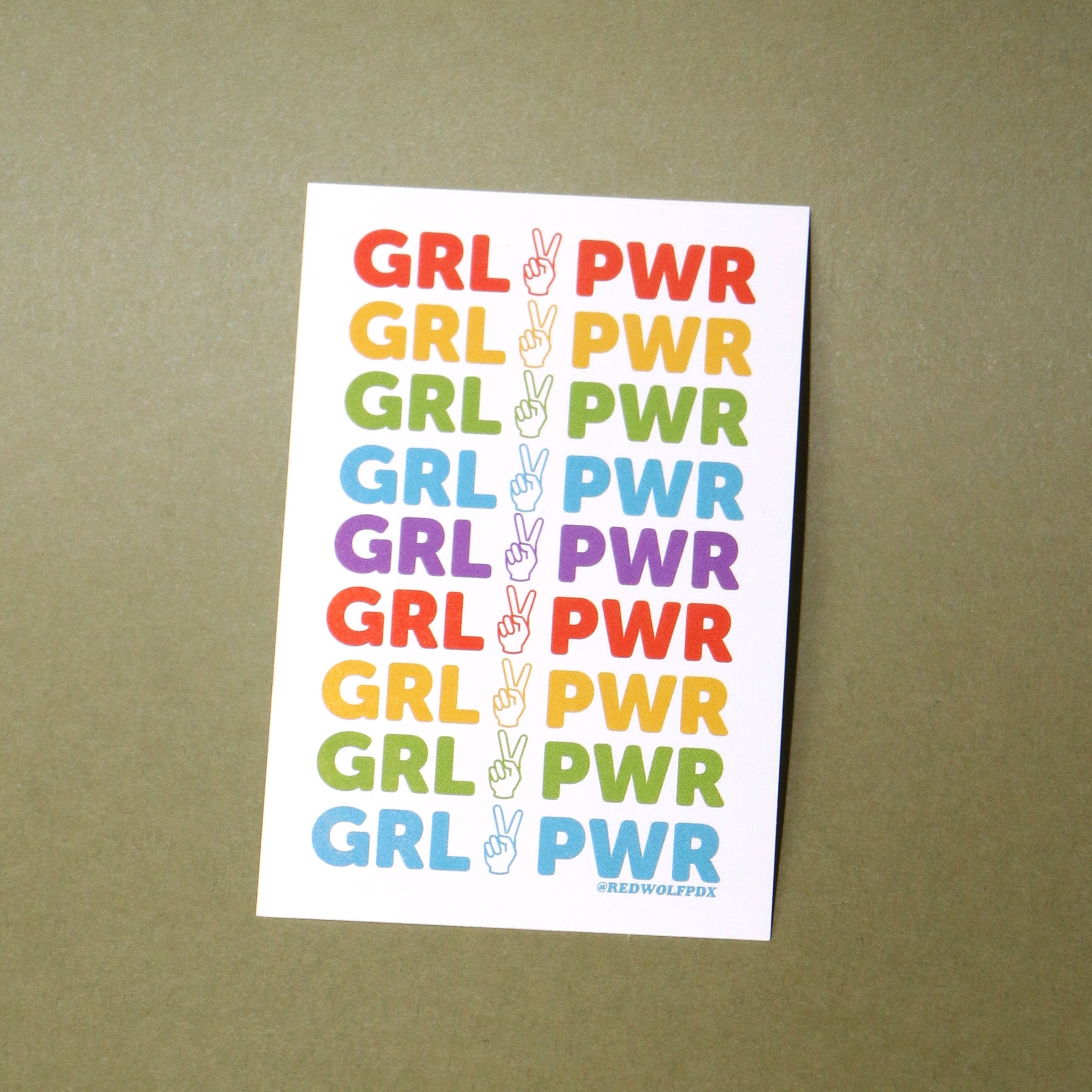 sticker with text 'GRL PWR' printed in rainbow colors against a vintage green background