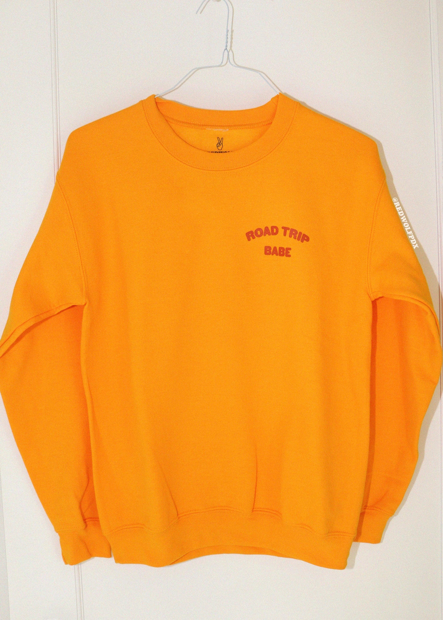 golden yellow sweatshirt with 'ROAD TRIP BABE' text on a white background