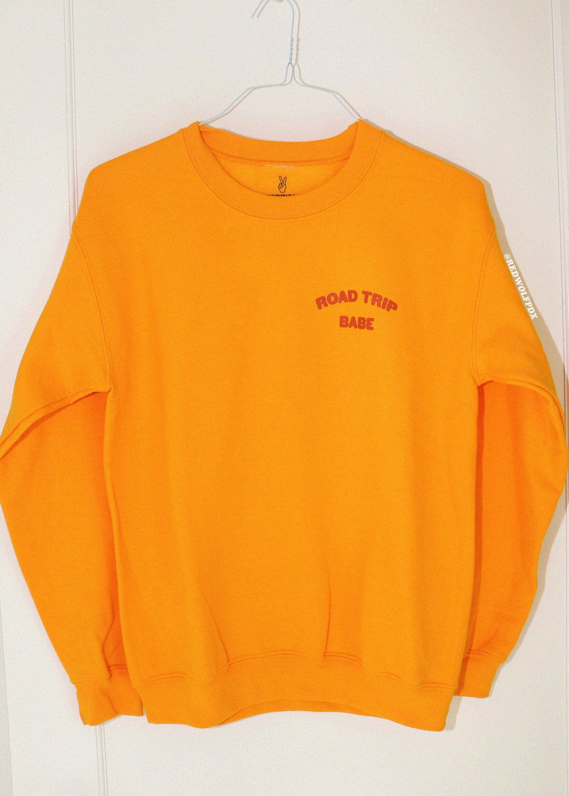 golden yellow sweatshirt with 'ROAD TRIP BABE' text on a white background