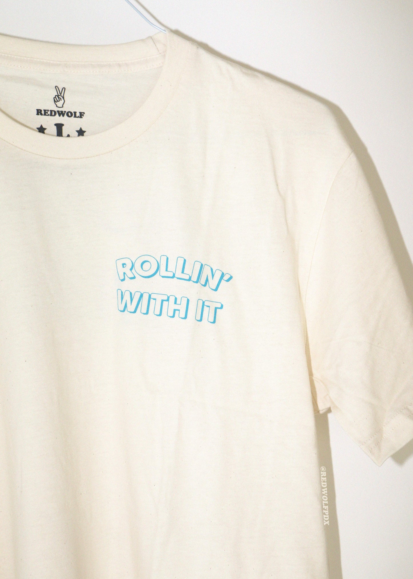 cream t-shirt with 'Rollin' With It' text on a white background