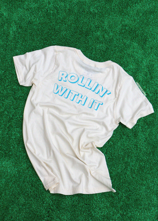 White t-shirt with 'Rollin' With It' text on a green textured background