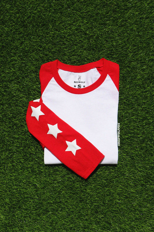 Folded red and white baseball-style shirt with star patterns on a green grass background