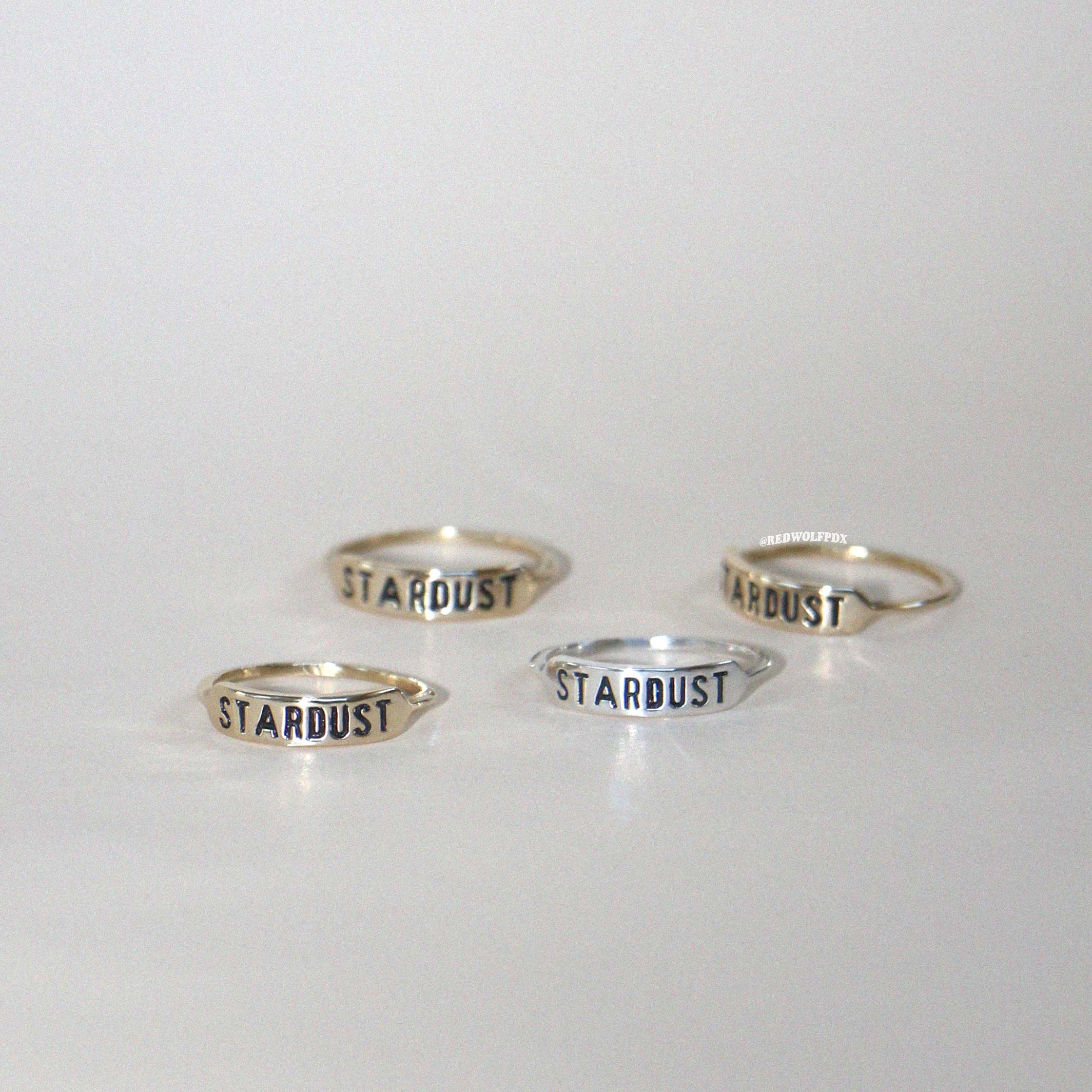 Four rings with the word 'STARDUST' engraved on them, displayed against a white background.