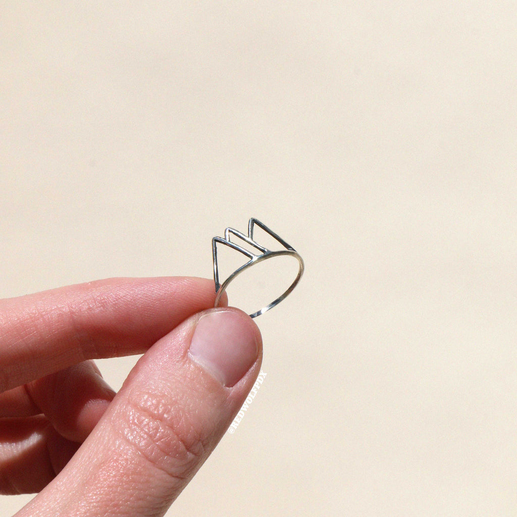 sterling silver mountain outline ring being held  against beige backdrop