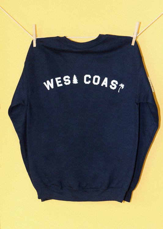 navy blue crewneck sweatshirt with the text 'WEST COAST' screen printed across the upper back in white ink hanging from a clothing line against a yellow backdrop