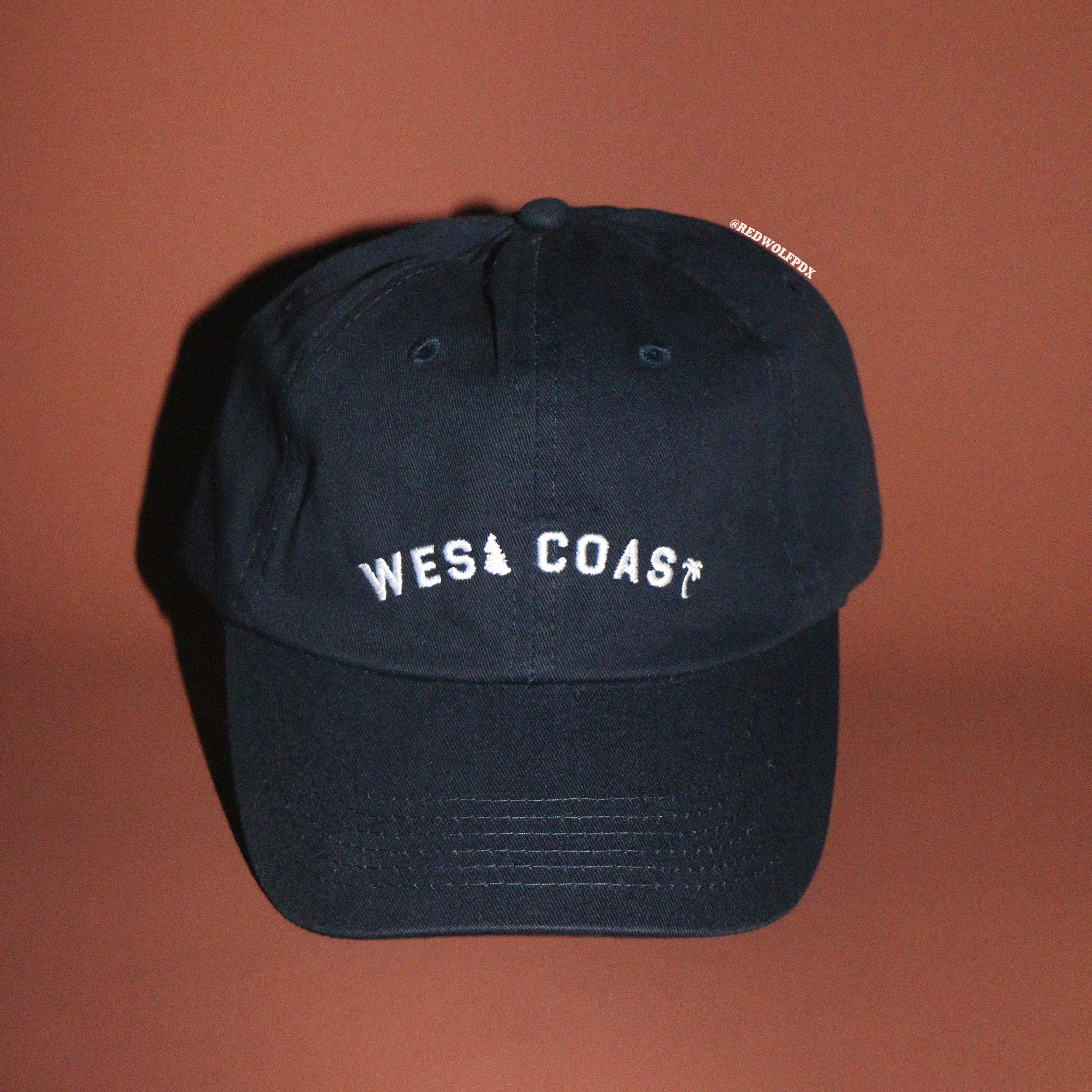 navy blue baseball  cap with 'West Coast' text on a brown background