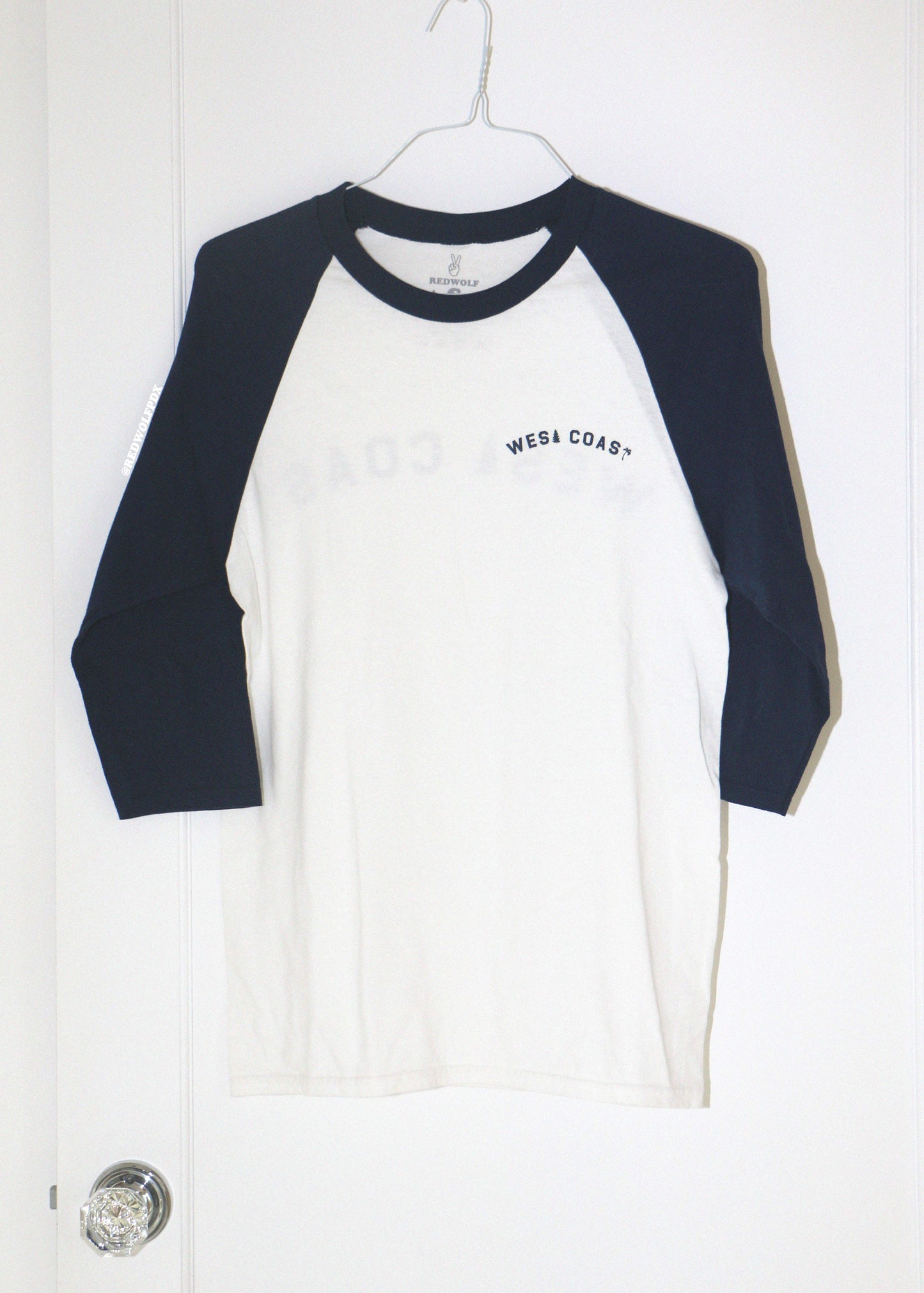 White and navy baseball shirt with 'West Coast' text on a white background